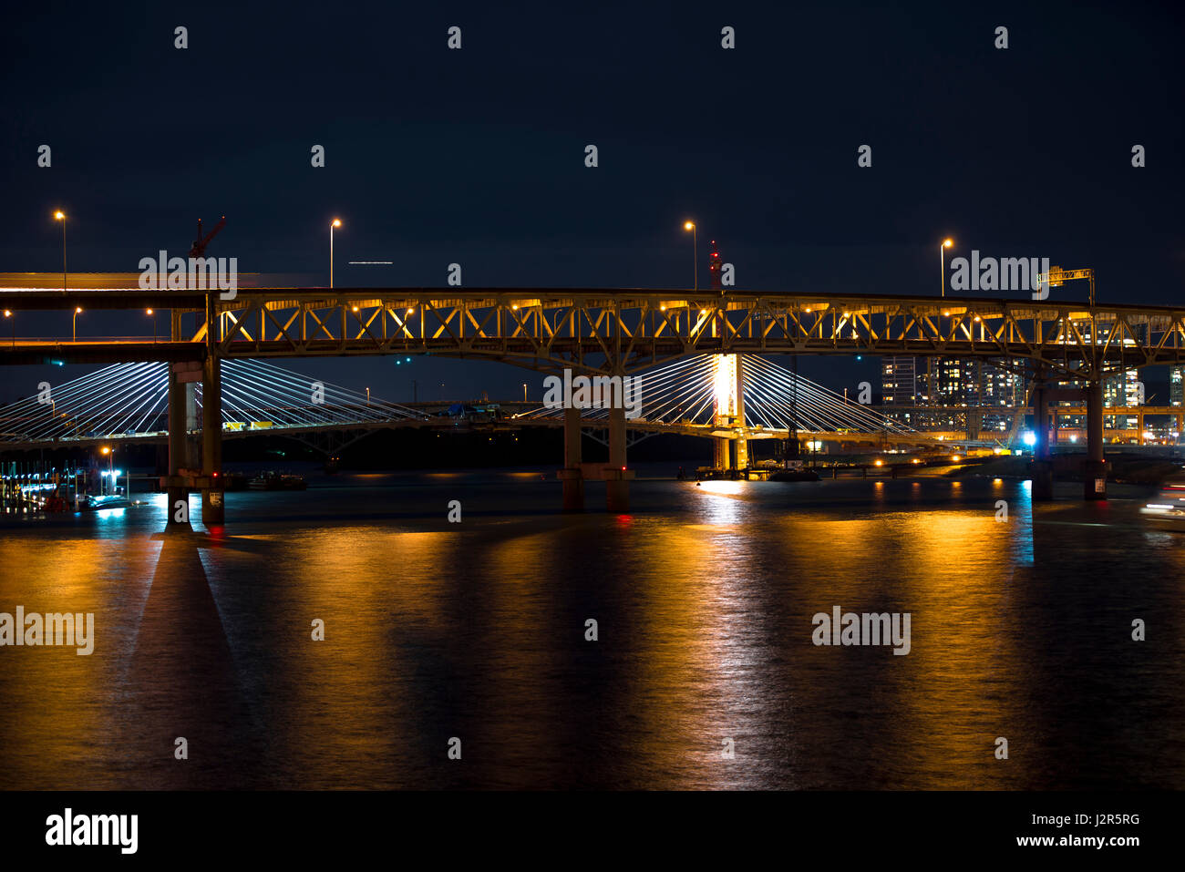 Modern rope and classic truss bridges across the evening river ...