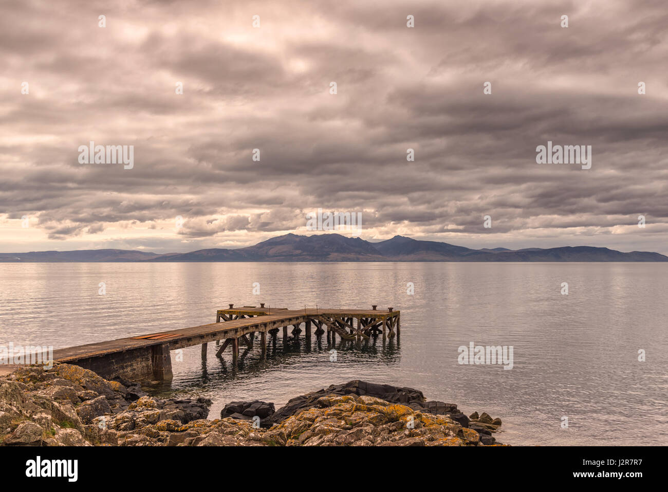 The ancient castle jetty at Portencross in Seamill Ayrshire Scotland with Arran hills in the back ground. The skys are heavy just before it rained as  Stock Photo