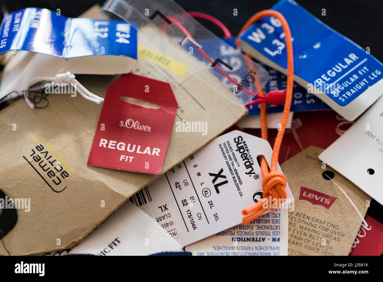 Large pile of various clothing brand label tags, removed from newly bought clothes after shopping. Labels show brand name, price, size etc. Stock Photo