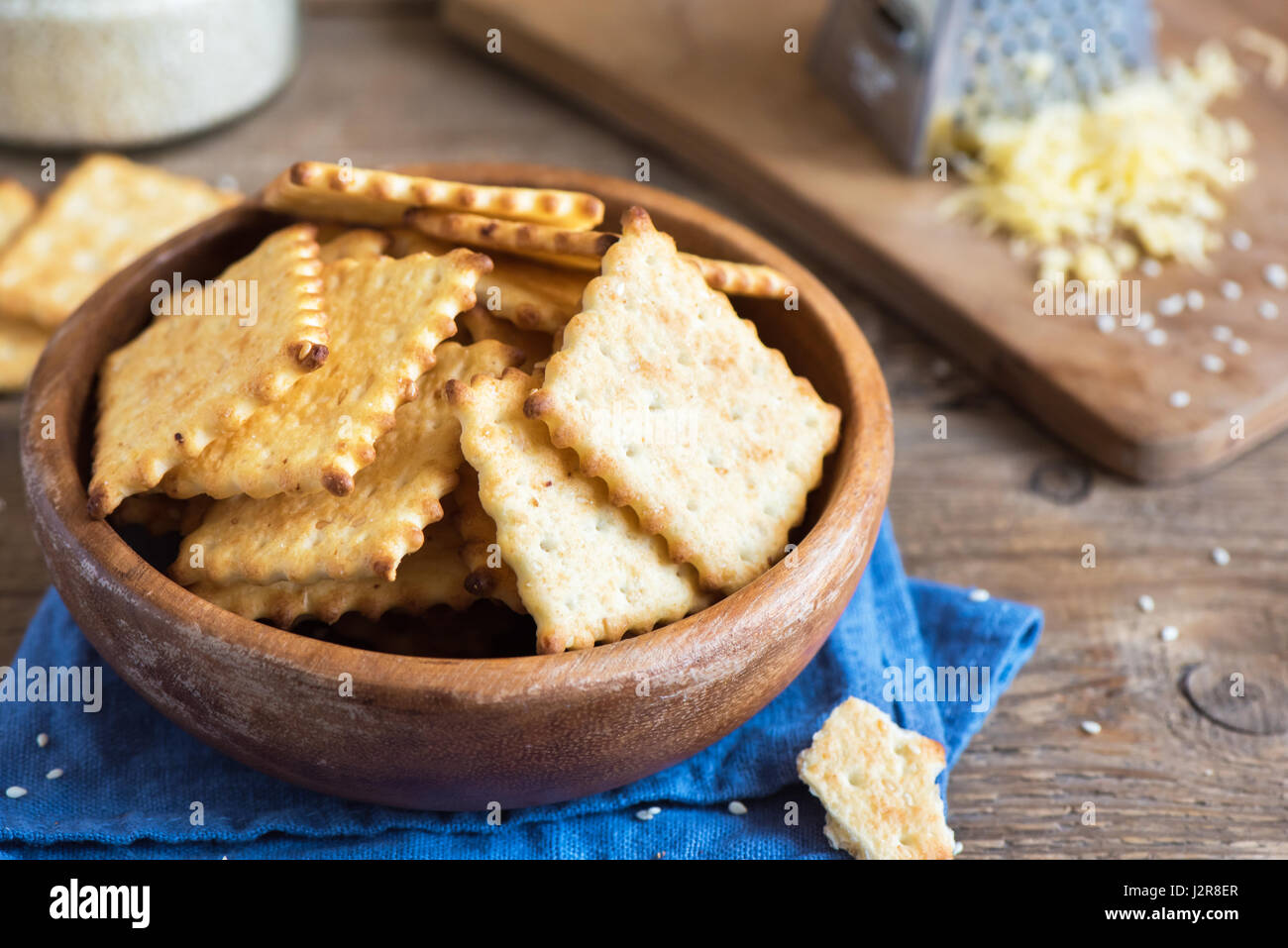 Homemade thin crispy cheesy crackers with sesame seeds in rustic wooden
