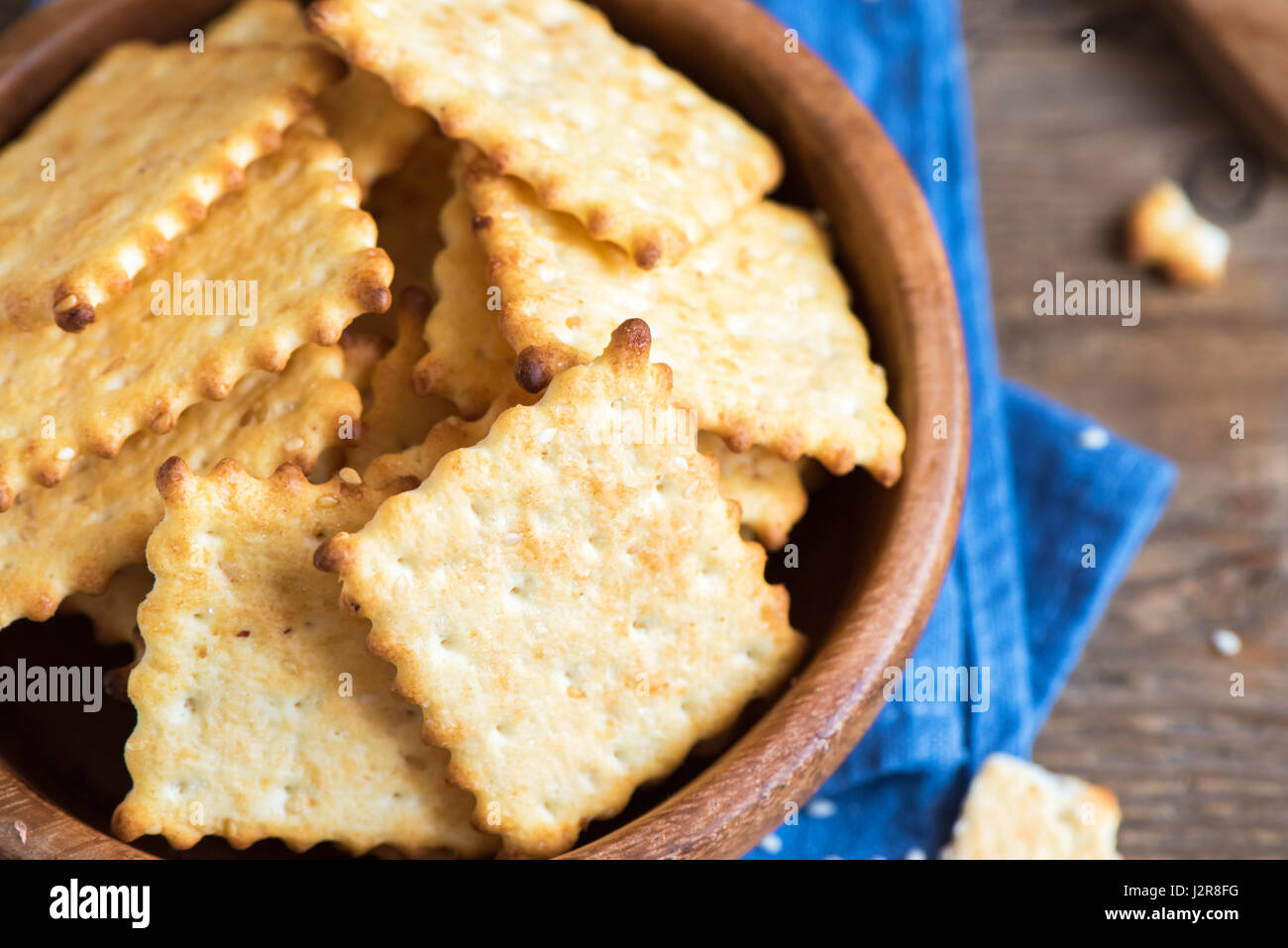 Homemade thin crispy cheesy crackers with sesame seeds in rustic wooden