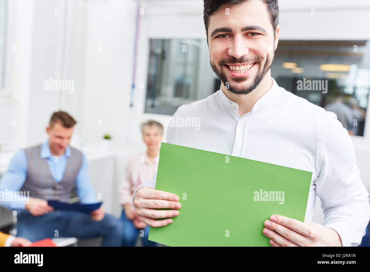 Young man holding blank sign in brainstorming workshop for creative ideas Stock Photo