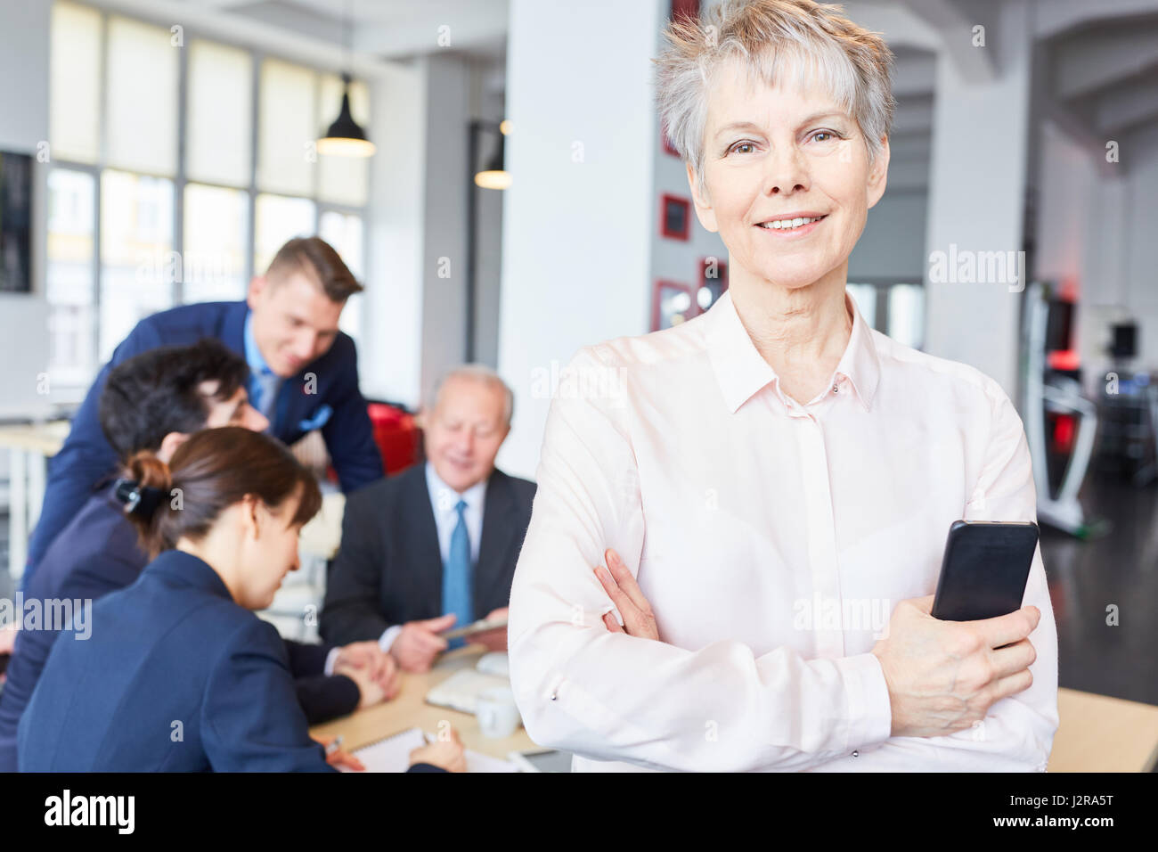 Senior businesswoman standing self confident next to her team Stock