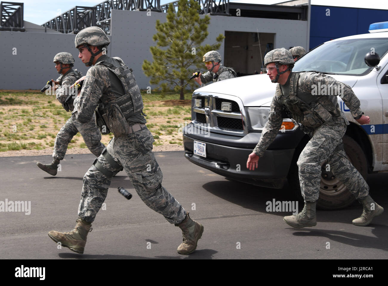 Members of the 460th Security Forces Squadron Emergency Services Team run towards a stopped vehicle prior to apprehending the suspect during a training event Apr. 23, 2017, at the Flatrock Regional Training Center in Commerce City, Colo. Adams County Sheriff Department Special Weapons and Tactics team members worked with the EST to help them learn the process of quickly, safely and effectively approaching a vehicle. (U.S. Air Force photo by Airman 1st Class Holden S. Faul/ Released) Stock Photo