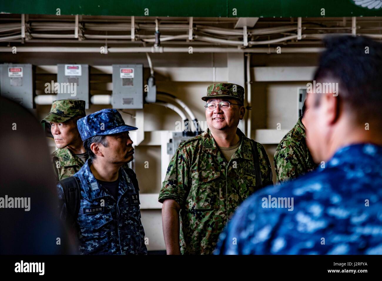 170427-N-JH293-038 SASEBO, Japan (April 27, 2017) Japan Self-Defense Force (JSDF) personnel take a tour of the amphibious transport dock USS Green Bay’s (LPD 20) hangar bay. Green Bay and other ships and units of Commander, Amphibious Force 7th Fleet, routinely partner with the JSDF to increase mutual understanding and interoperability to further strengthen the U.S.-Japan Alliance. (U.S. Navy photo by Mass Communication Specialist 1st Class Chris Williamson/Released) Stock Photo
