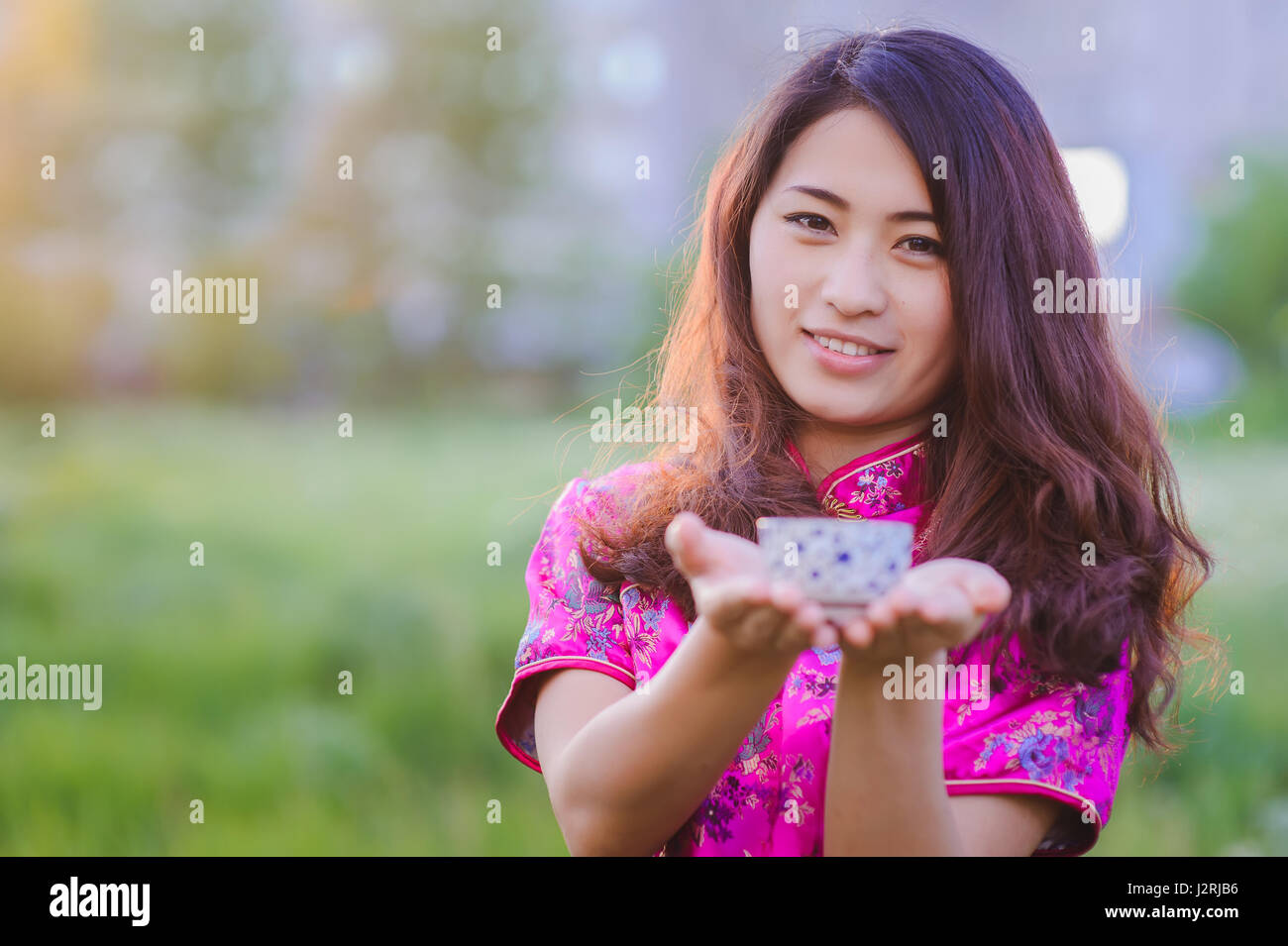 Young Chinese smiling girl pouring tea In traditional Chinese clothes