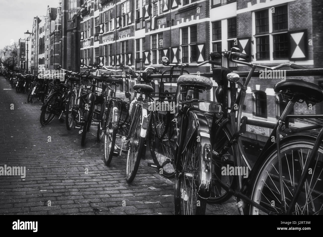 Amsterdam, Netherlands – October 30, 2016: Bikes parked against the railing of the canal Oudezijds Kolk in the center of Amsterdam. Stock Photo