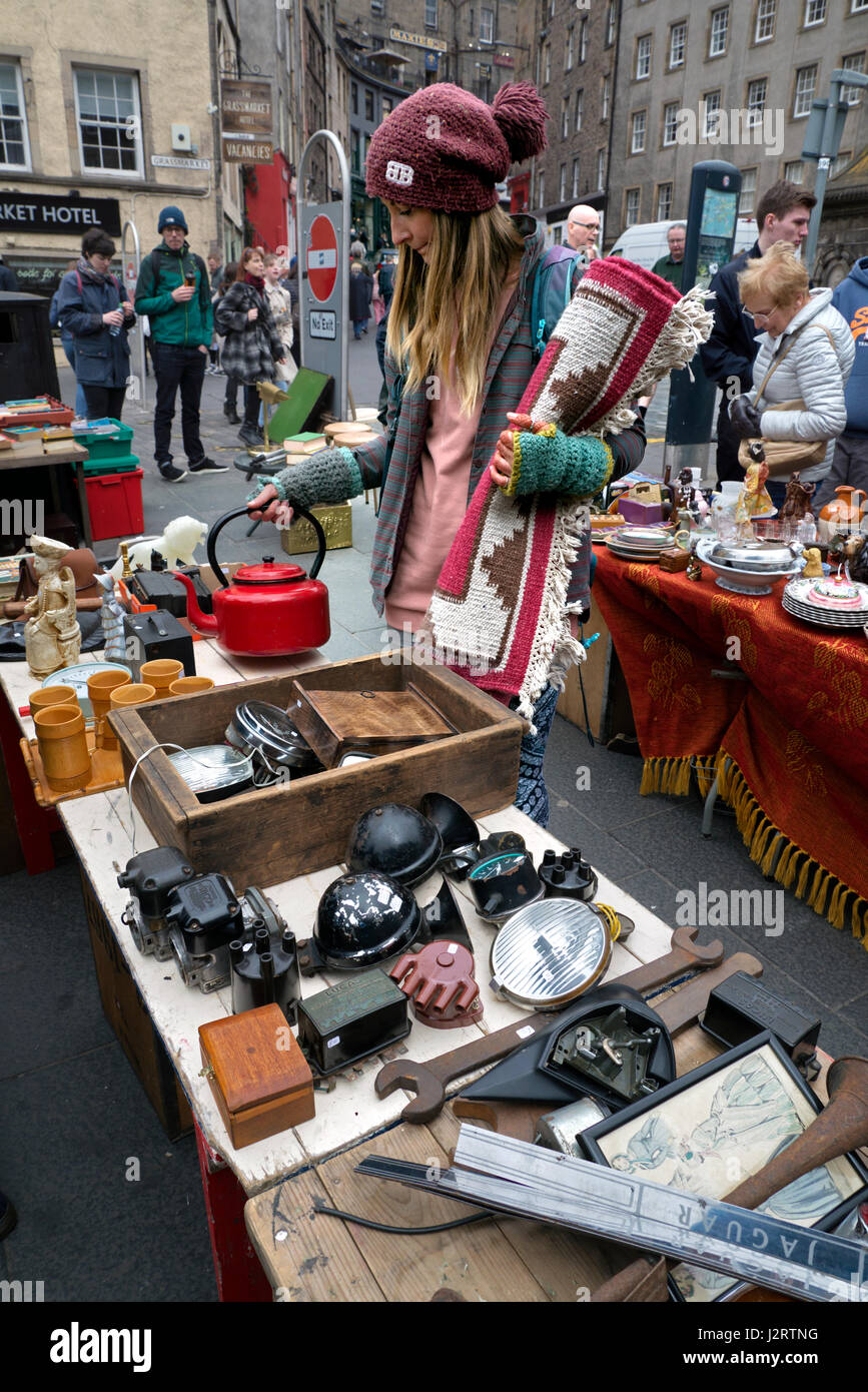 A young woman with a rug browsing the stalls at a fleamarket in the Grassmarket, Edinburgh, Scotland, UK. Stock Photo