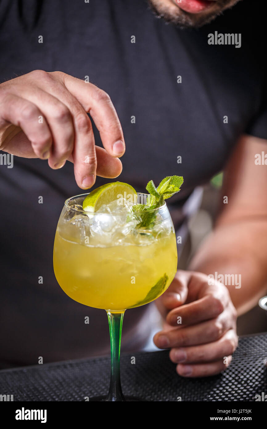 Bartender putting lime into glass, barman is decorating cocktail Stock Photo Alamy