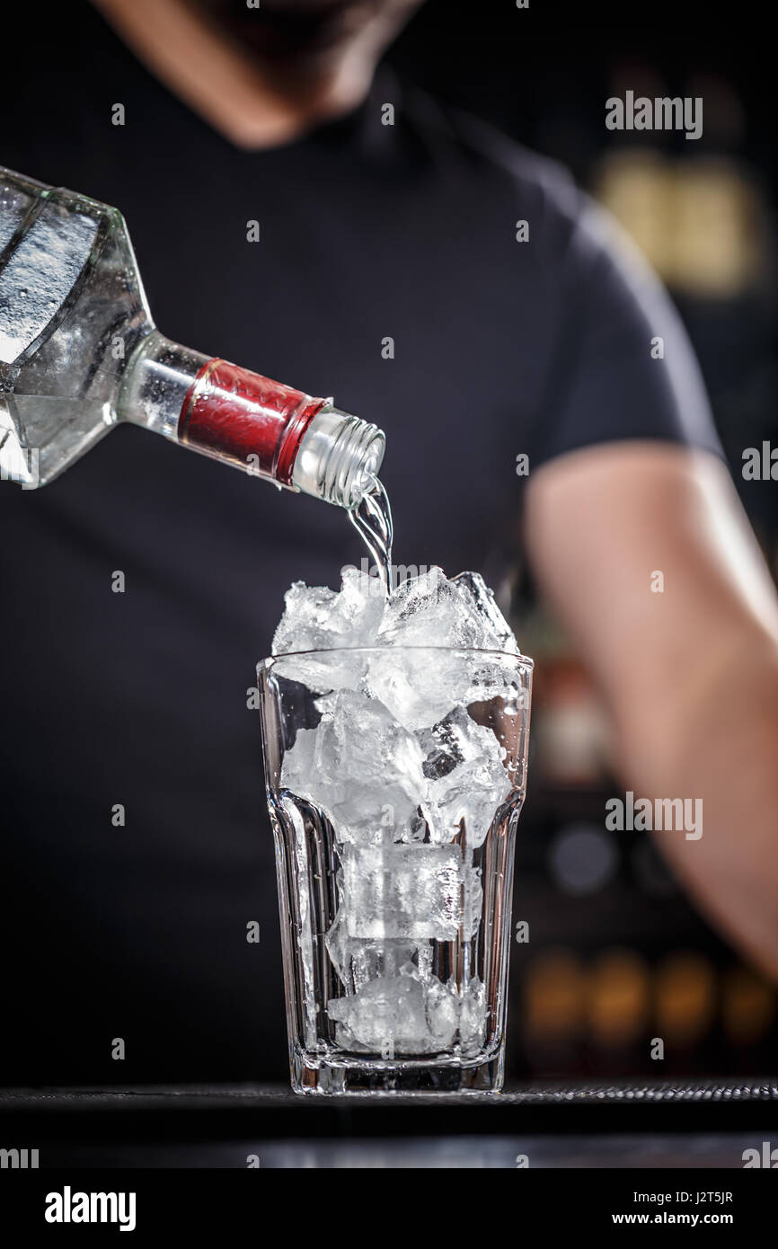 Bartender is pouring tequila into glass, he is preparing cocktail Stock
