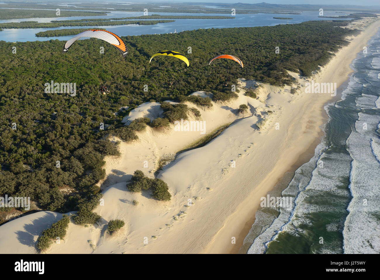 AIR-TO-AIR VIEW. Fleet of paramotors above the beach of South Stradbroke Island. Gold Coast, Queensland, Australia. Stock Photo