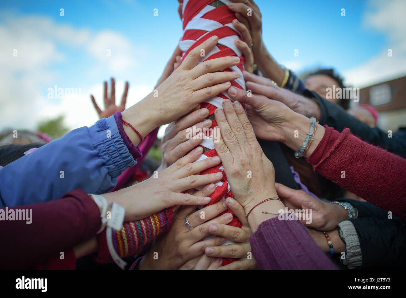 Hands touch the maypole at the Chalice Well, Glastonbury, where Beltane festivities are taking place on May Day. Stock Photo