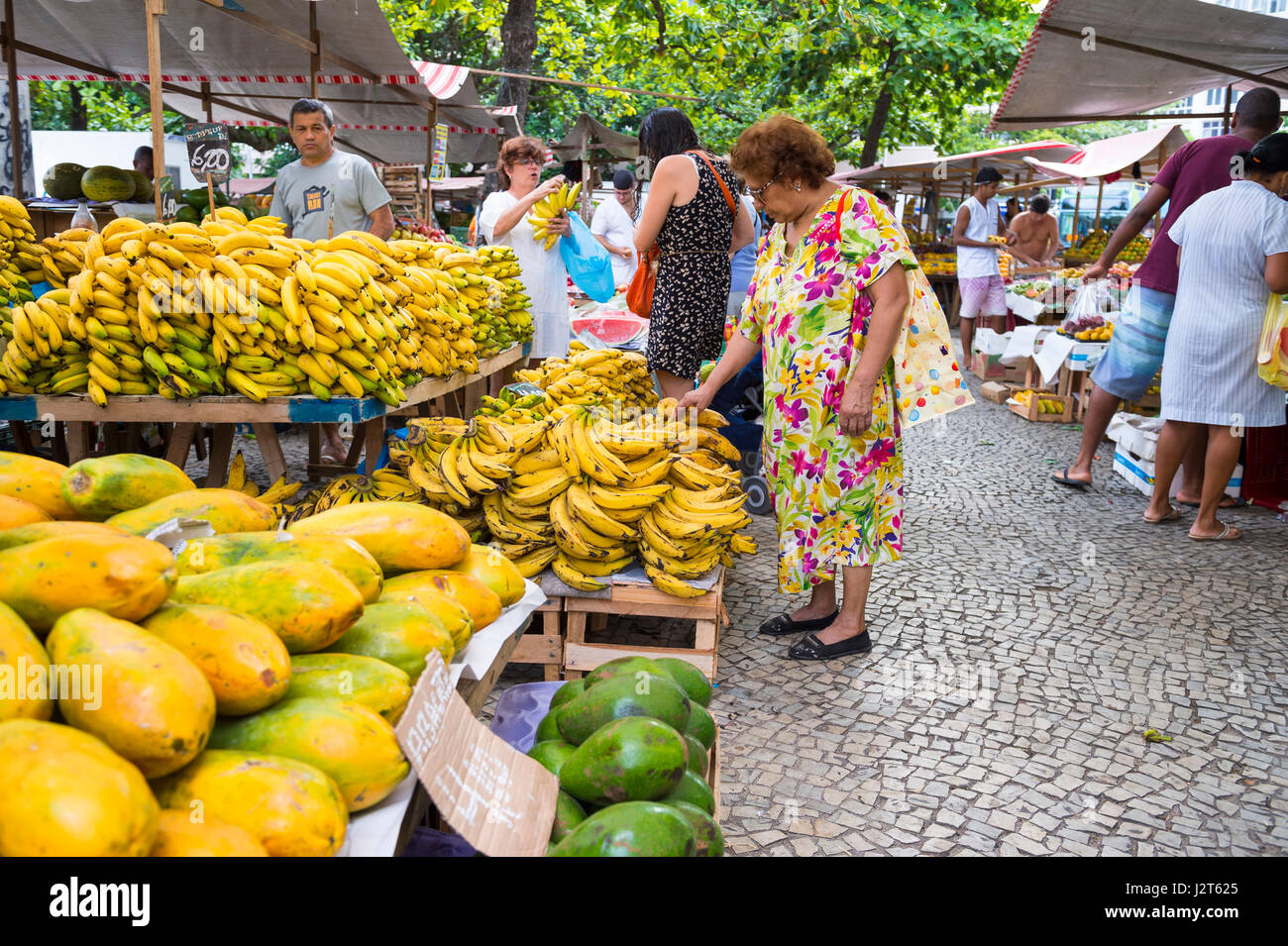 RIO DE JANEIRO - JANUARY 31, 2017: Brazilian customers browse the colorful stalls stacked with tropical fruit at the weekly farmers market in Ipanema. Stock Photo