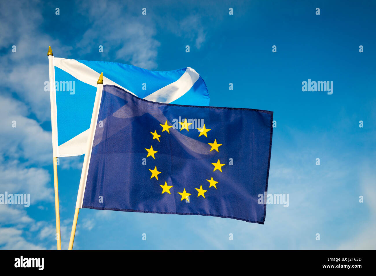 EU European Union and Scottish flag flying together in bright blue sky Stock Photo