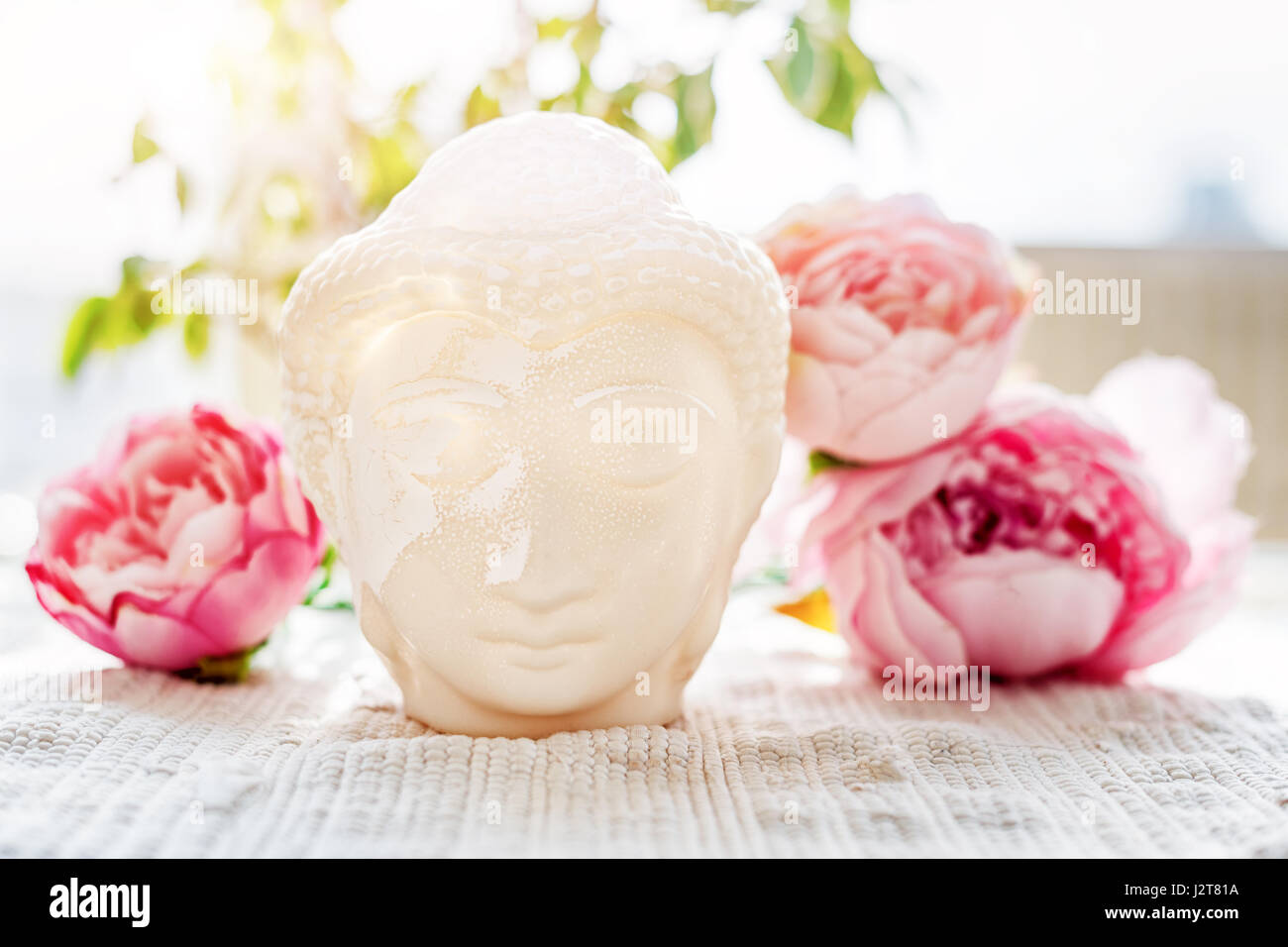 Buddha face. Buddha statue made of white marble with flowers. Concept