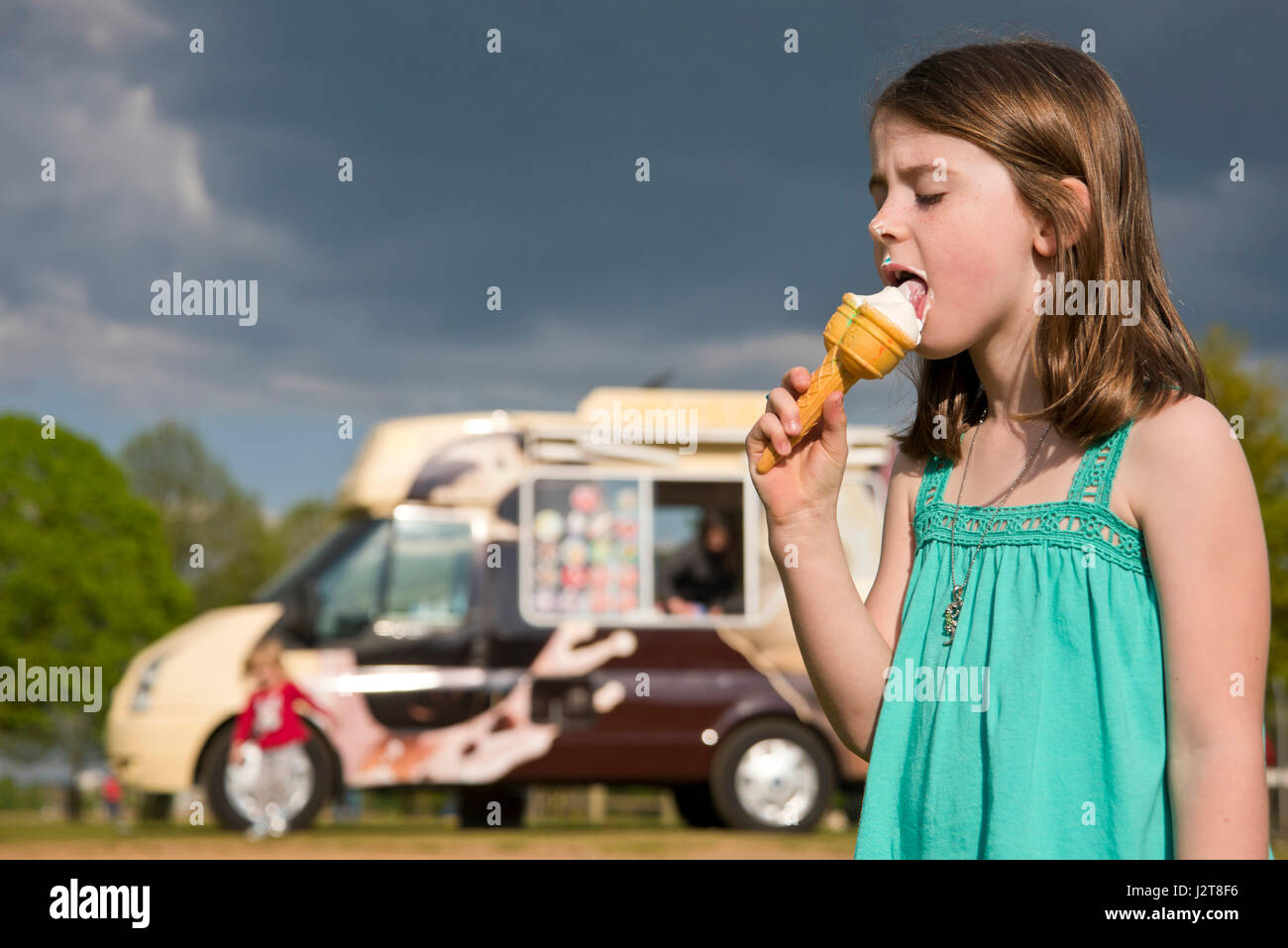 Horizontal portrait of a child eating ice cream in the sun. Stock Photo