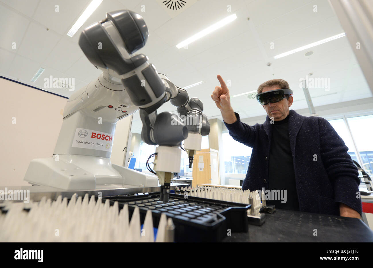 Renningen, Germany. 27th Apr, 2017. A worker of the robotics laboratory working with holo-glasses and the learnable, two-armed manufactoring-robot Youmi in the robotics laboratory at the Bosch Forschungscampus research campus in Renningen, Germany, 27 April 2017. Photo: Franziska Kraufmann/dpa/Alamy Live News Stock Photo