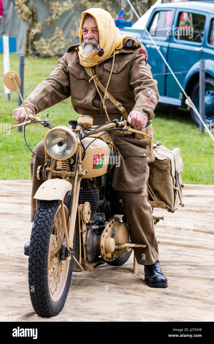 England, Sandwich. Salute to the 40s event. Mature man from the Desert Rat Living History group about to ride off on a vintage motor-cycle. Smoking a pipe. Stock Photo
