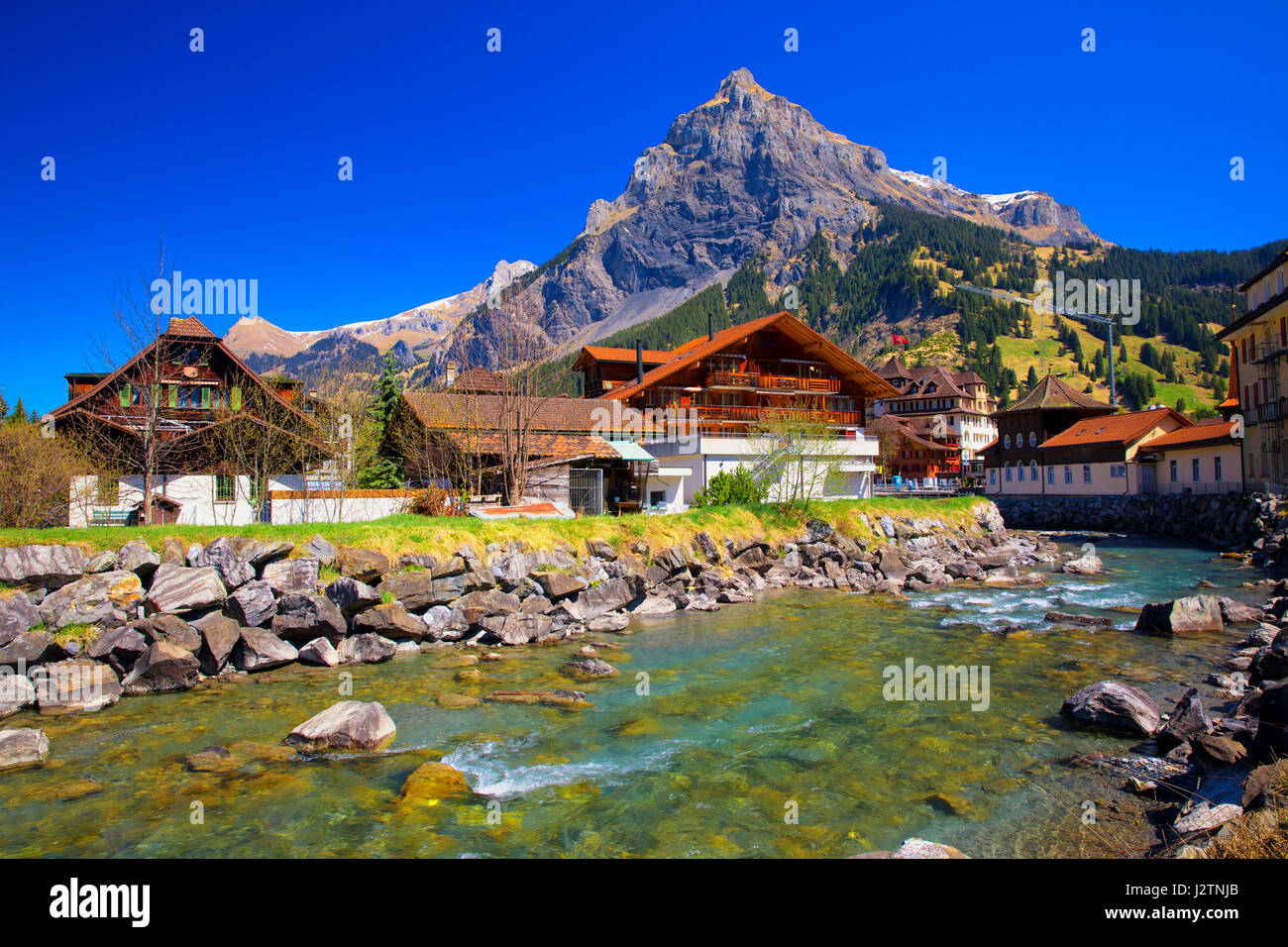 KANDERSTEGG, SWITZERLAND - April 2017 - Colorful wooden houses with flowers in Kandersteg village, Canton Bern, Switzerland, Europe. Stock Photo