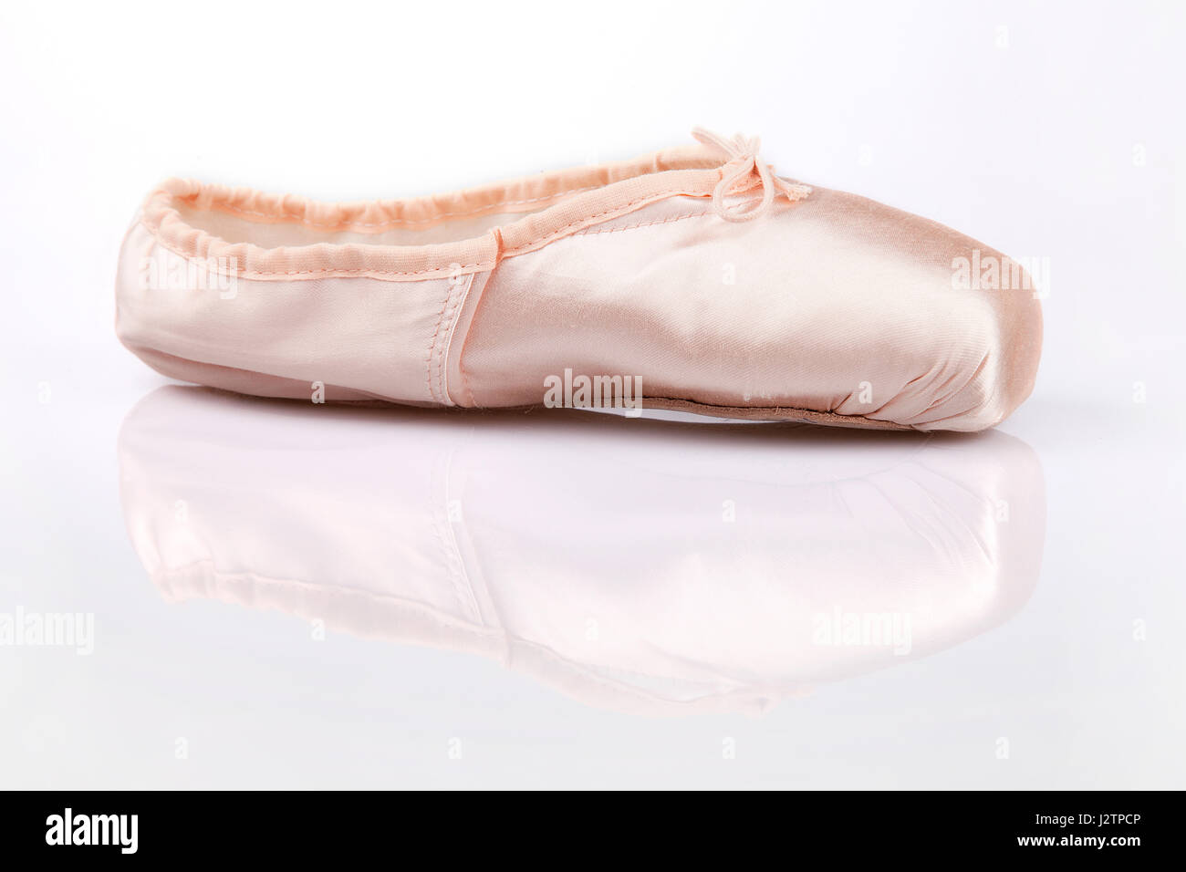 Pretty pink satin ballerina dancing shoe on a white surface. Pointe