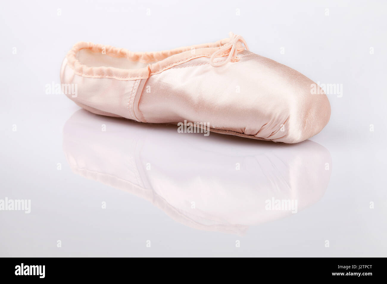 Pretty pink satin ballerina dancing shoe on a white surface. Pointe