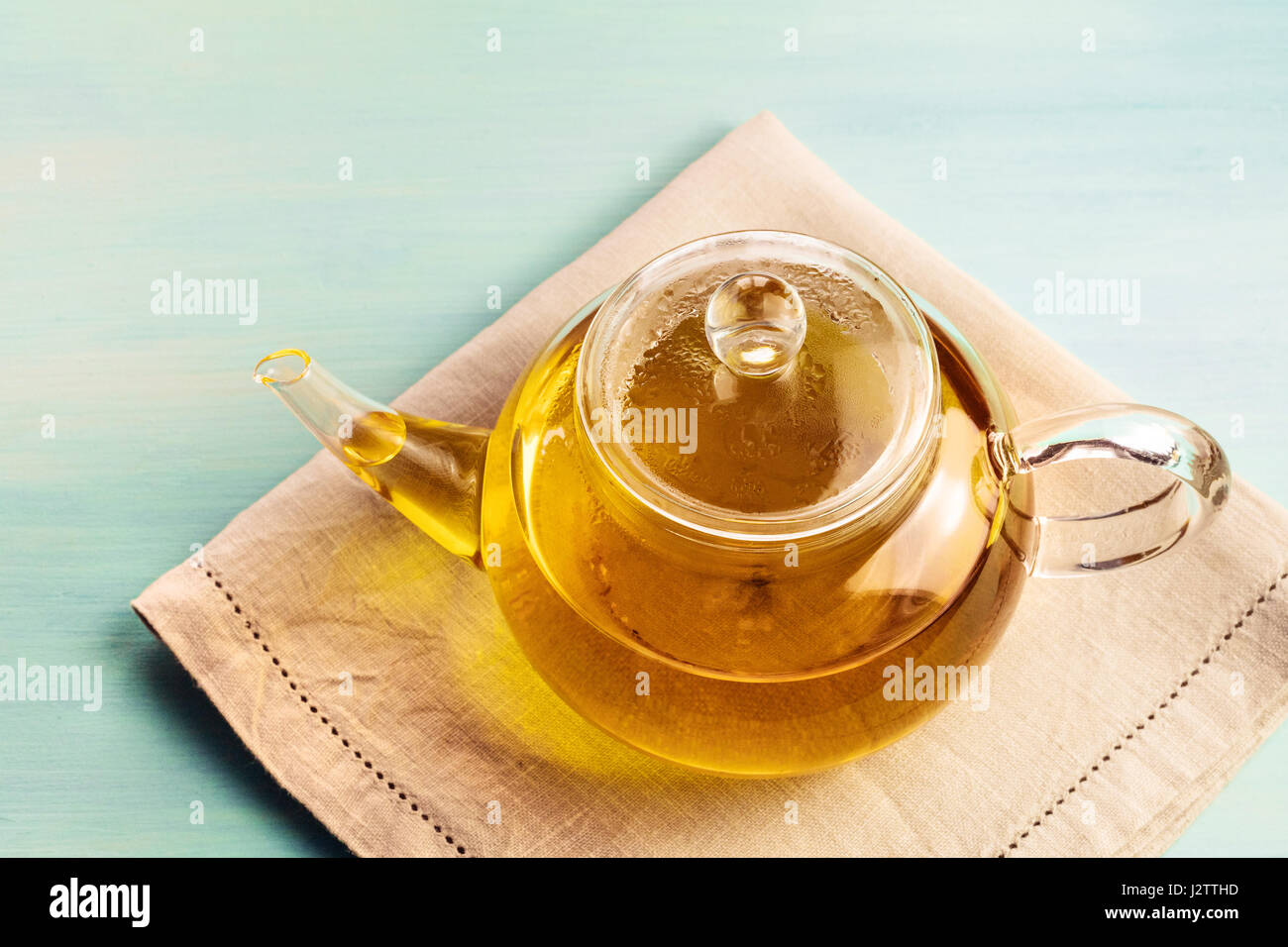 A photo of a teapot full of tea, shot on a teal texture with a place