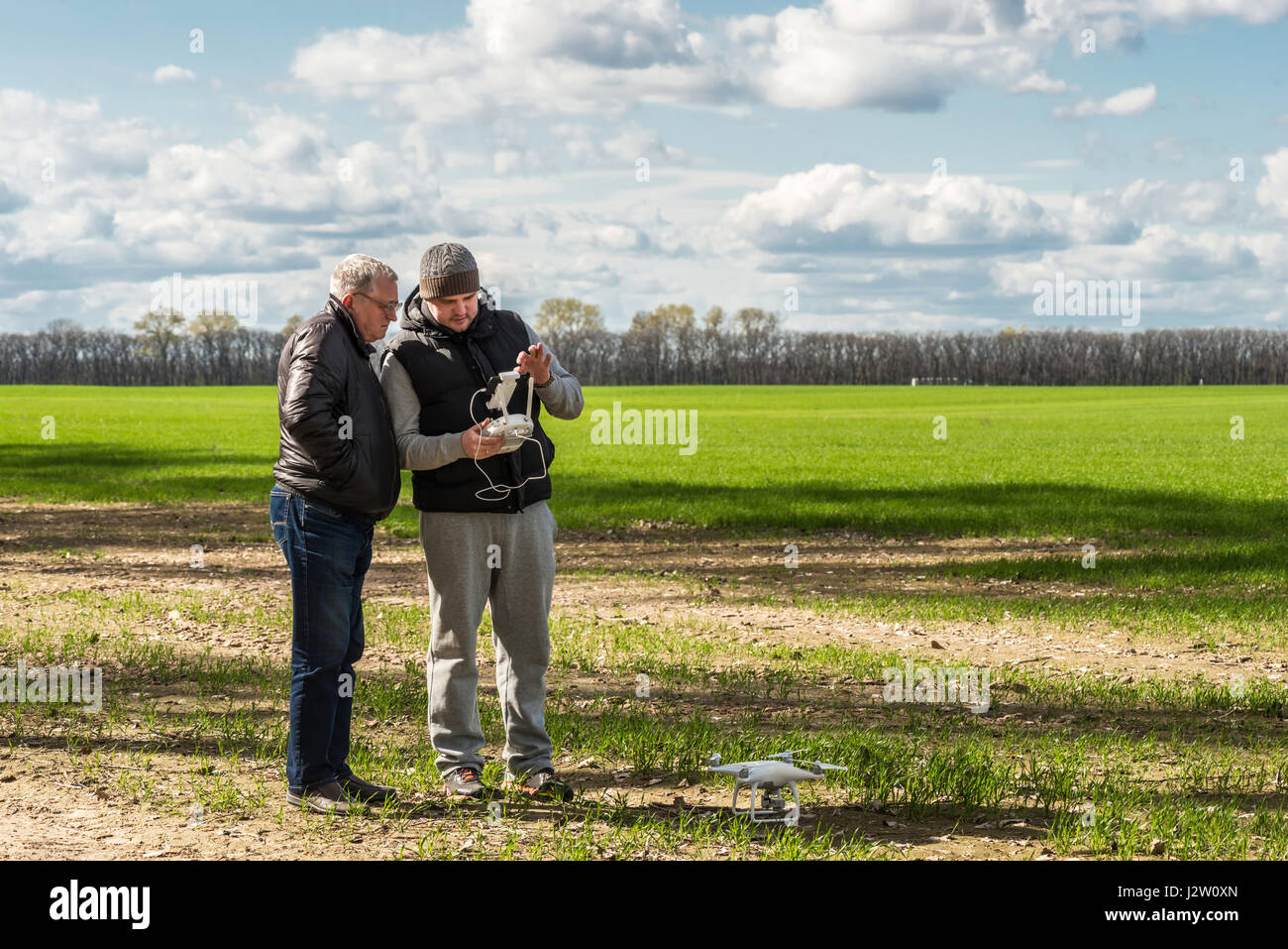 two men playing with the drone at the green field Stock Photo - Alamy