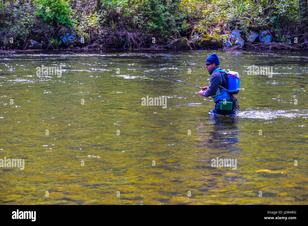 Man in blue fly fishing in the Ariege River, France Stock Photo