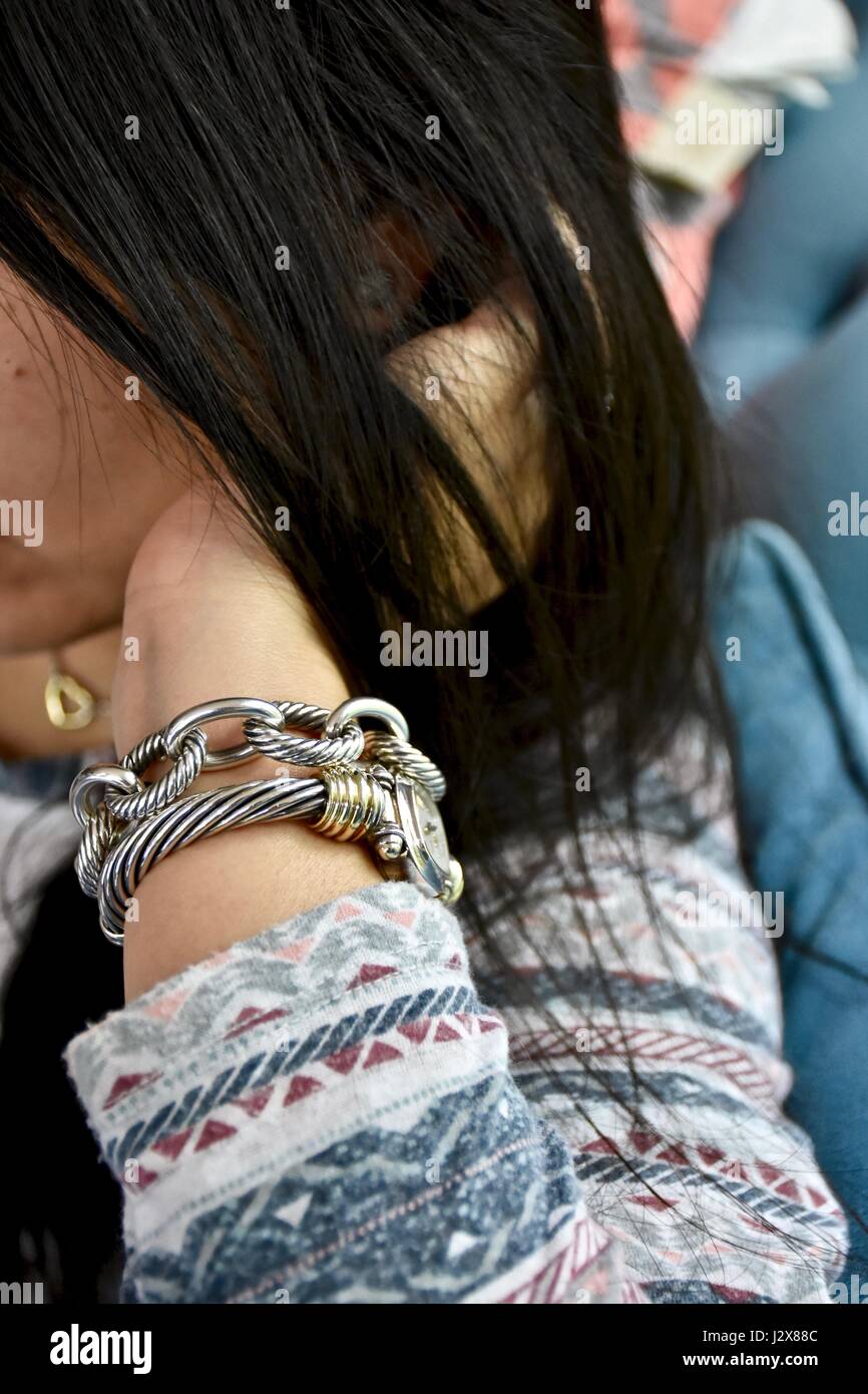 Stressed out woman with hand on head wearing David Yurman jewelry on her wrist Stock Photo