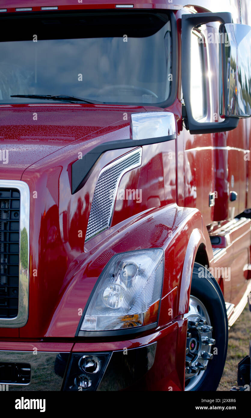 Modern powerful economical shiny red semi truck wet from the rain with