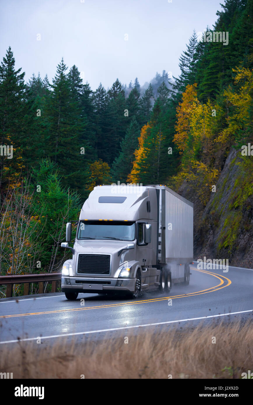 Modern professional long haul heavy semi truck with lights on and