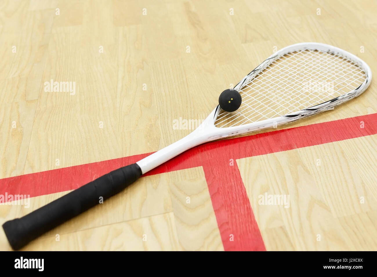 white squash racket and ball on the wooden floor. Racquetball equipment