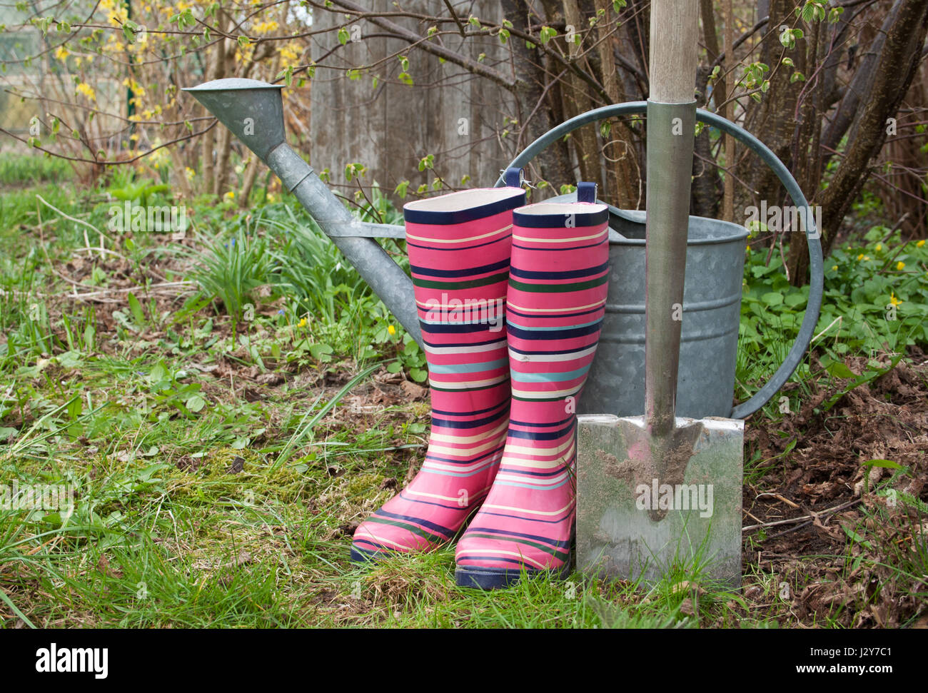 Rubber boots, spade and watering can in the garden Stock Photo