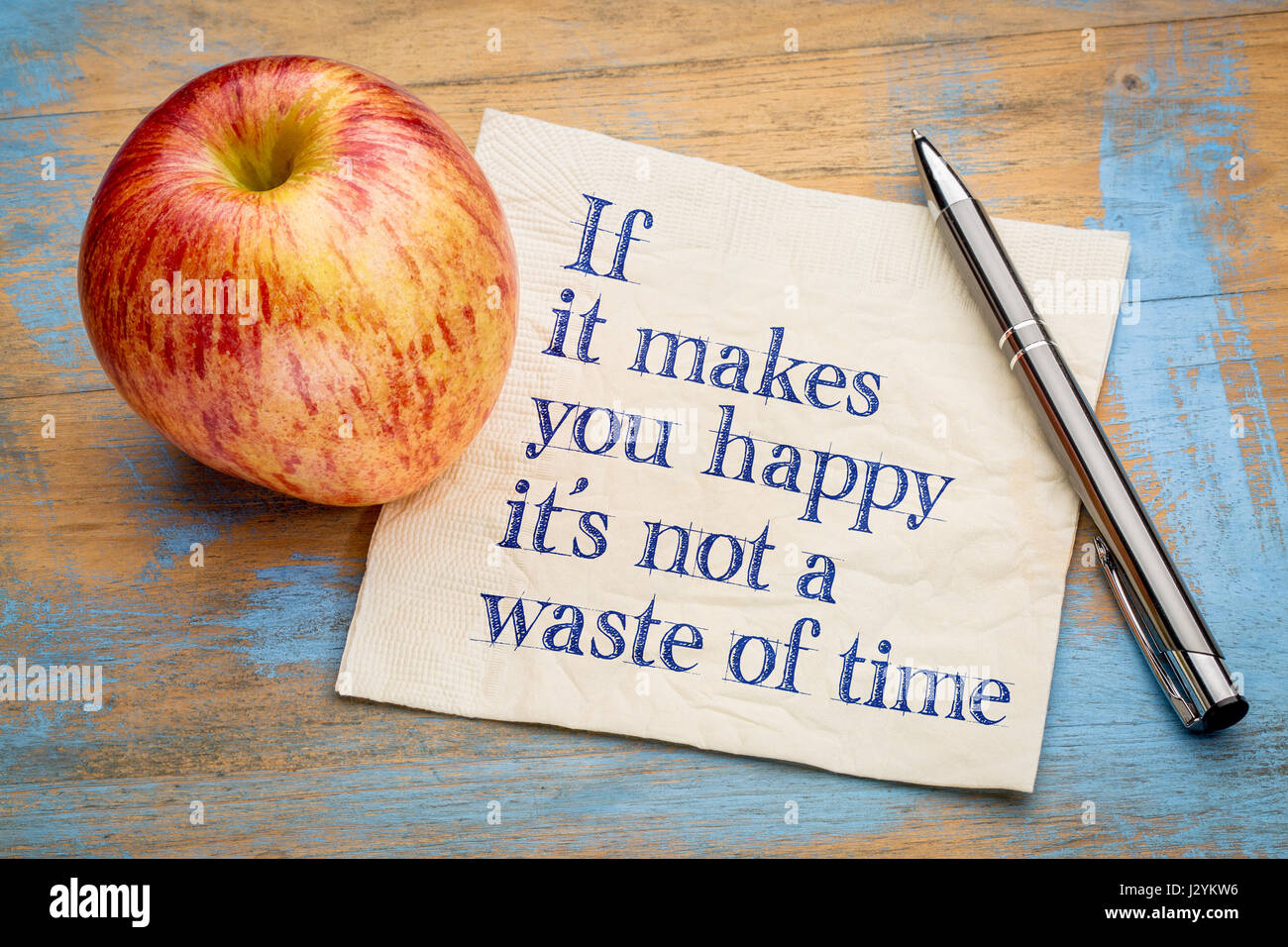 If it makes you happy it is not a waste of time - inspirational handwriting on a napkin with a fresh apple Stock Photo