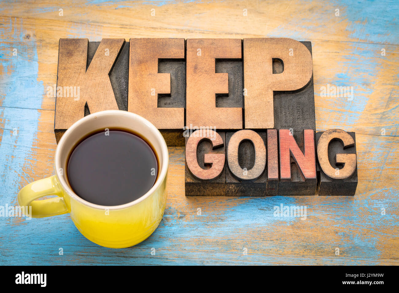 Keep going motivation word abstract in vintage letterpress wood type blocks with a cup of coffee Stock Photo