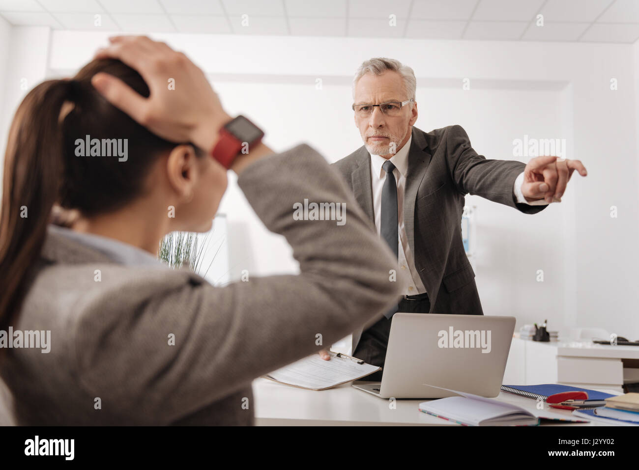Angry boss standing opposite his secretary Stock Photo