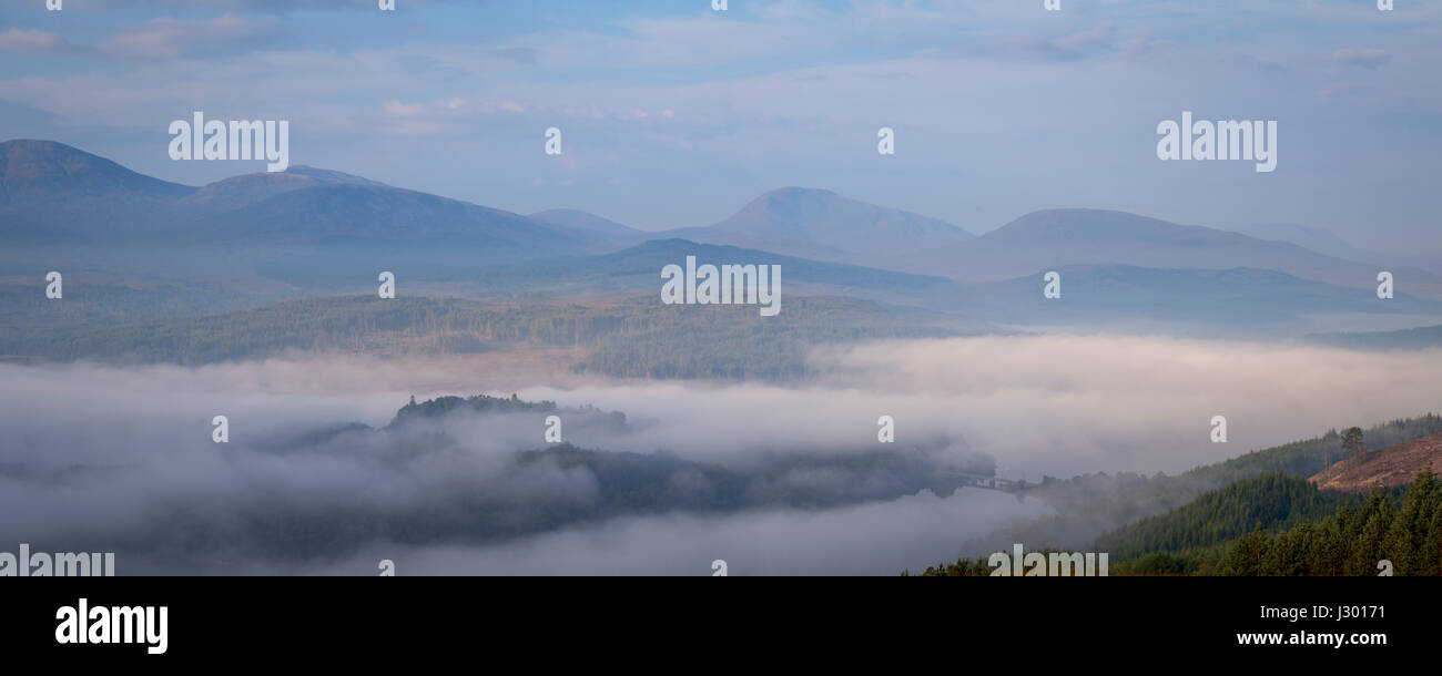 Panoramic view of Loch Garry at sunrise covered by morning mist/cloud inversion on a peaceful summer's morning. Stock Photo