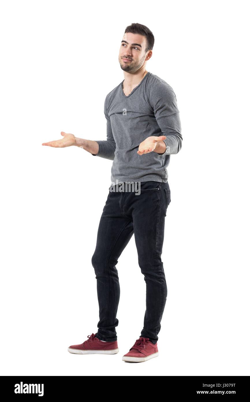 Clueless confused young man shrugging shoulders looking away. Full body length portrait isolated over white studio background. Stock Photo