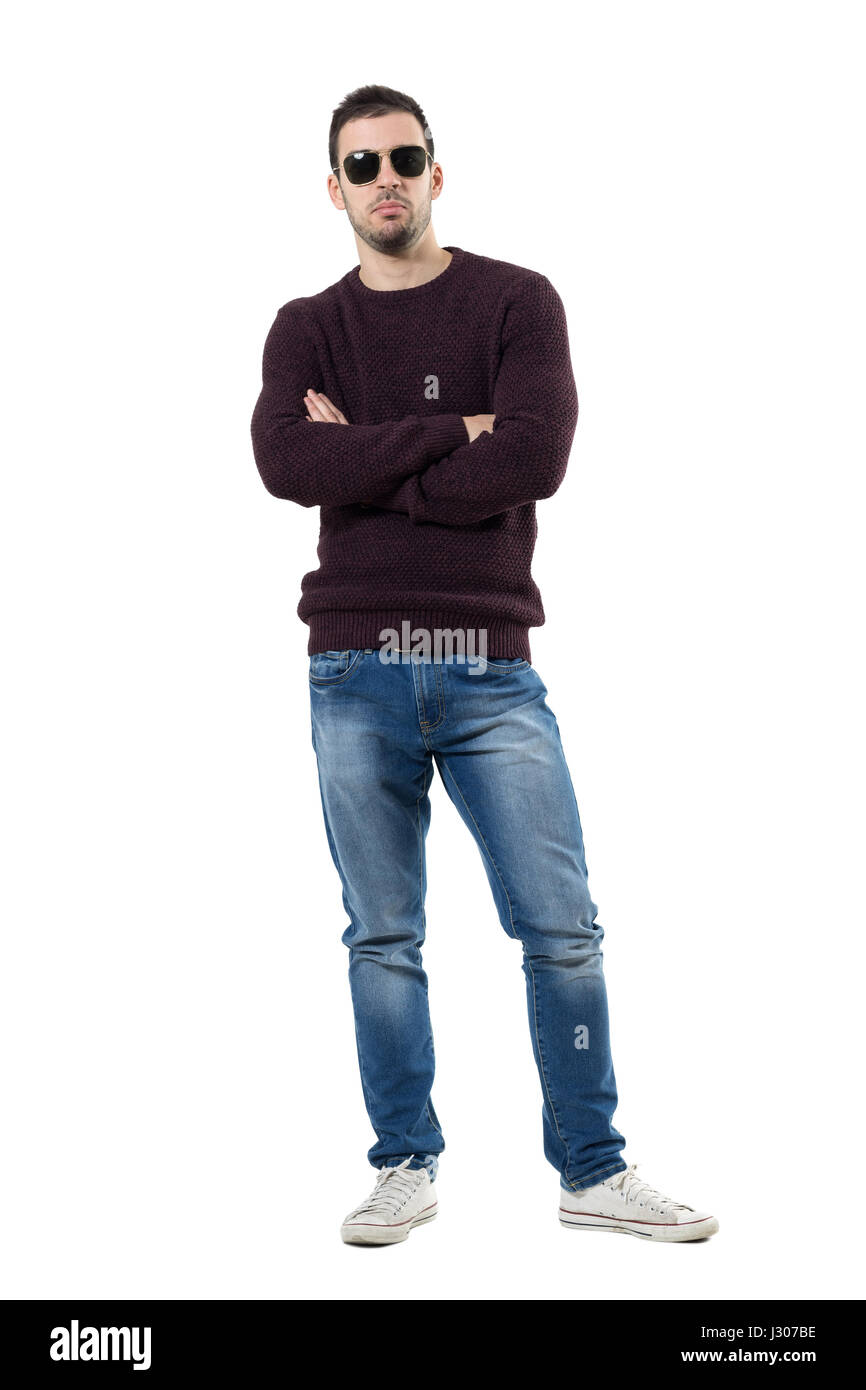 Young man with crossed arms judging and sulking at camera. Full body length portrait isolated over white studio background. Stock Photo