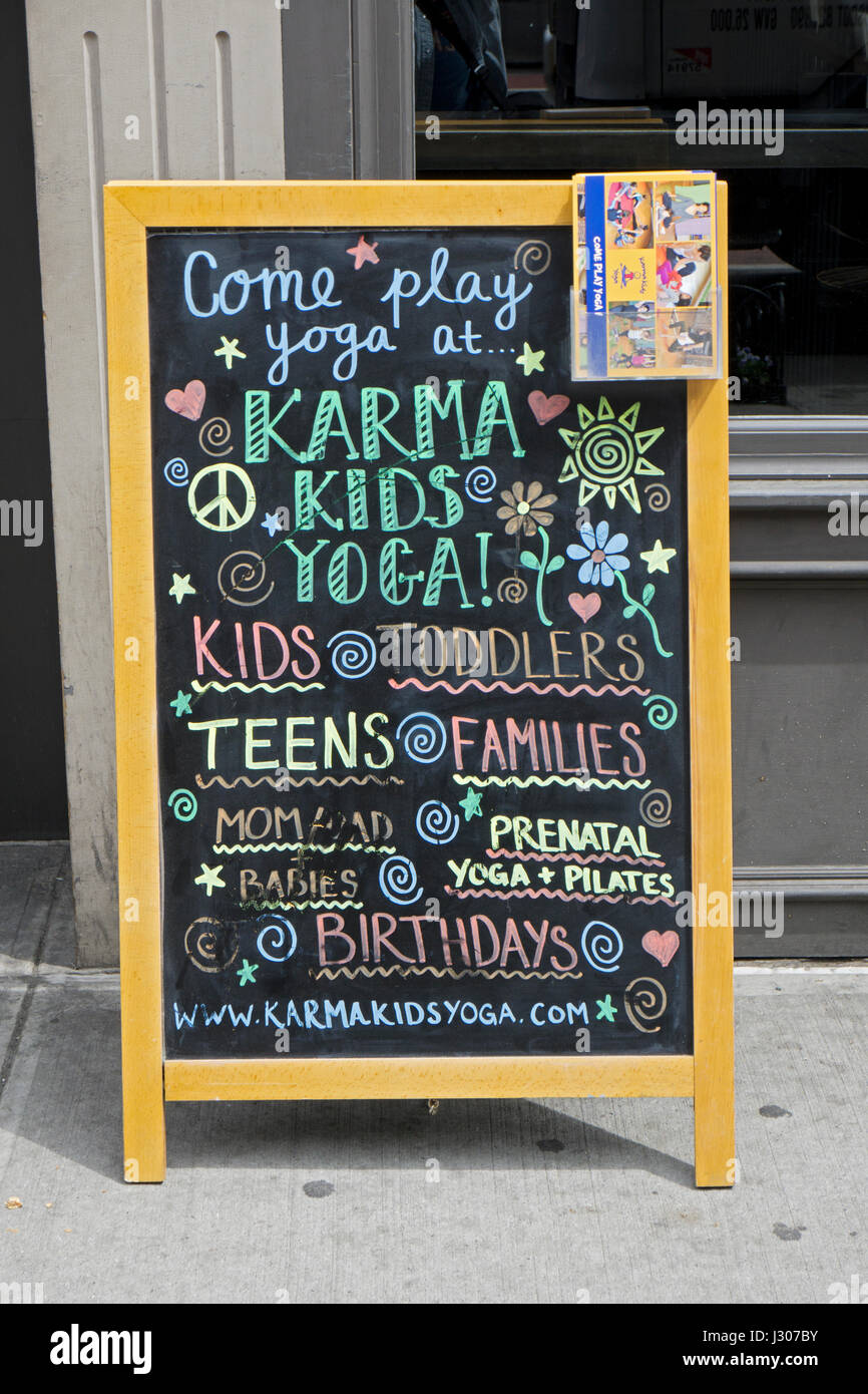 A chalkboard advertisement for Karma Kids Yoga, a yoga studio that specializes in yoga for children. On West 23rd St. in the Chelsea section of NYC. Stock Photo