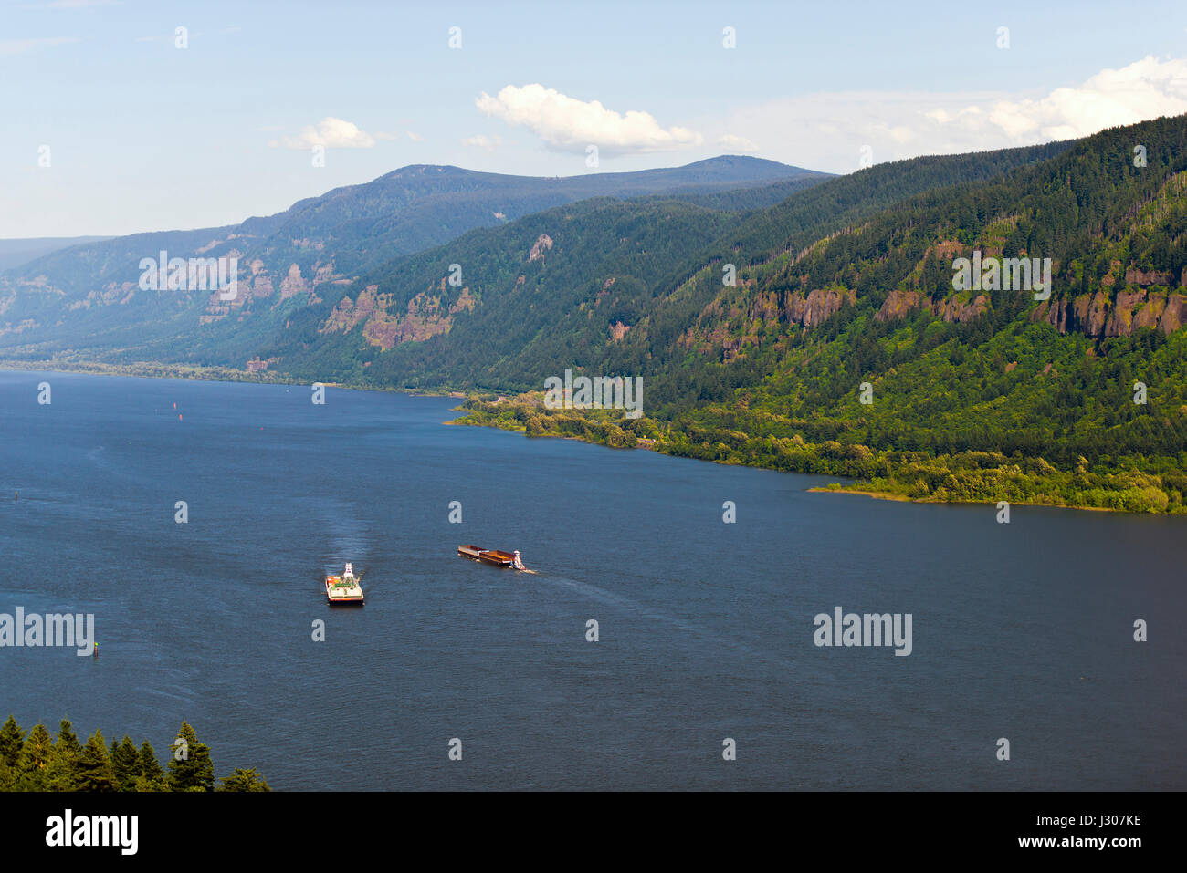 Two barges float towards each other on a wide Columbia River in