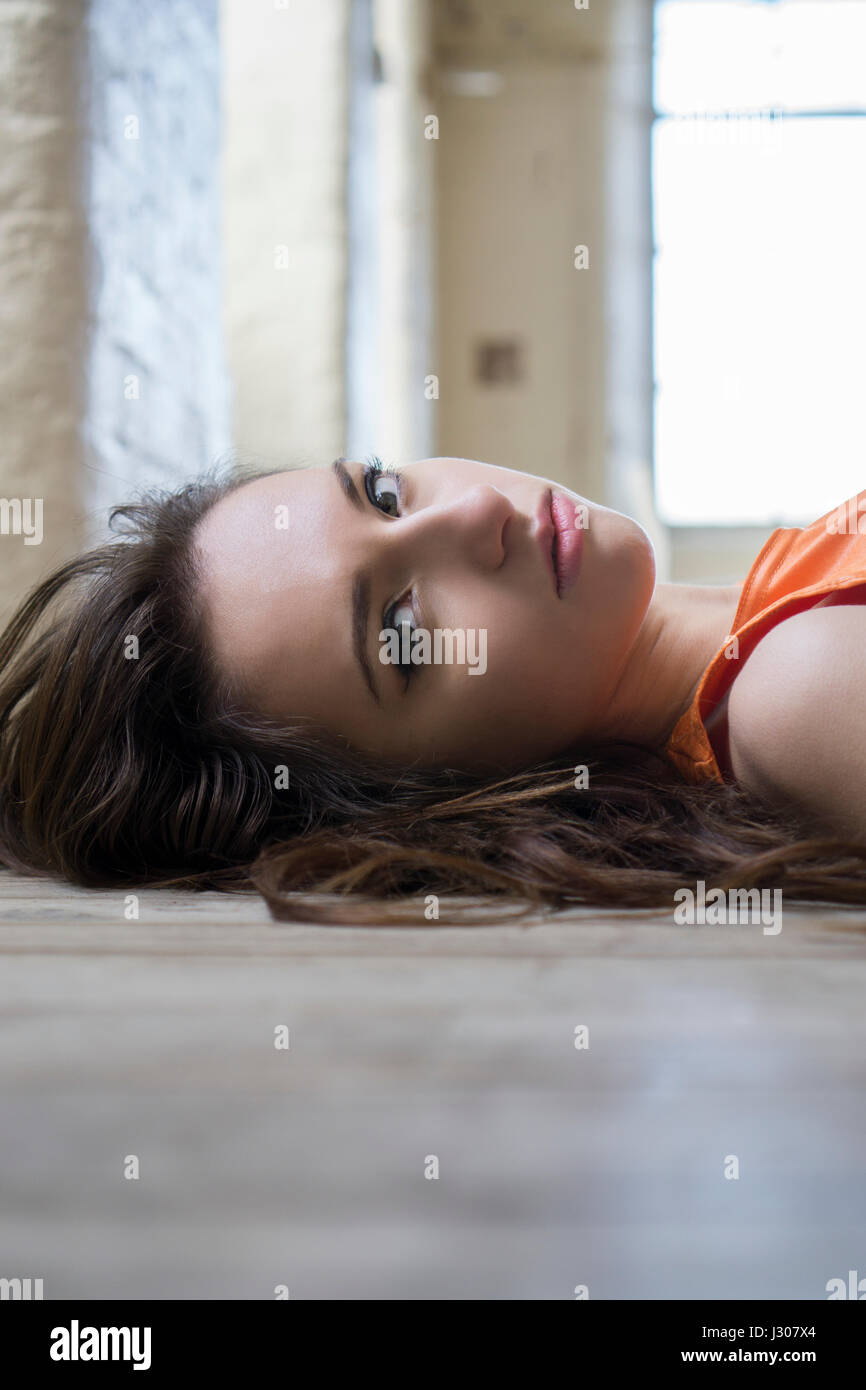 Sad young woman laying down on the floor Stock Photo - Alamy