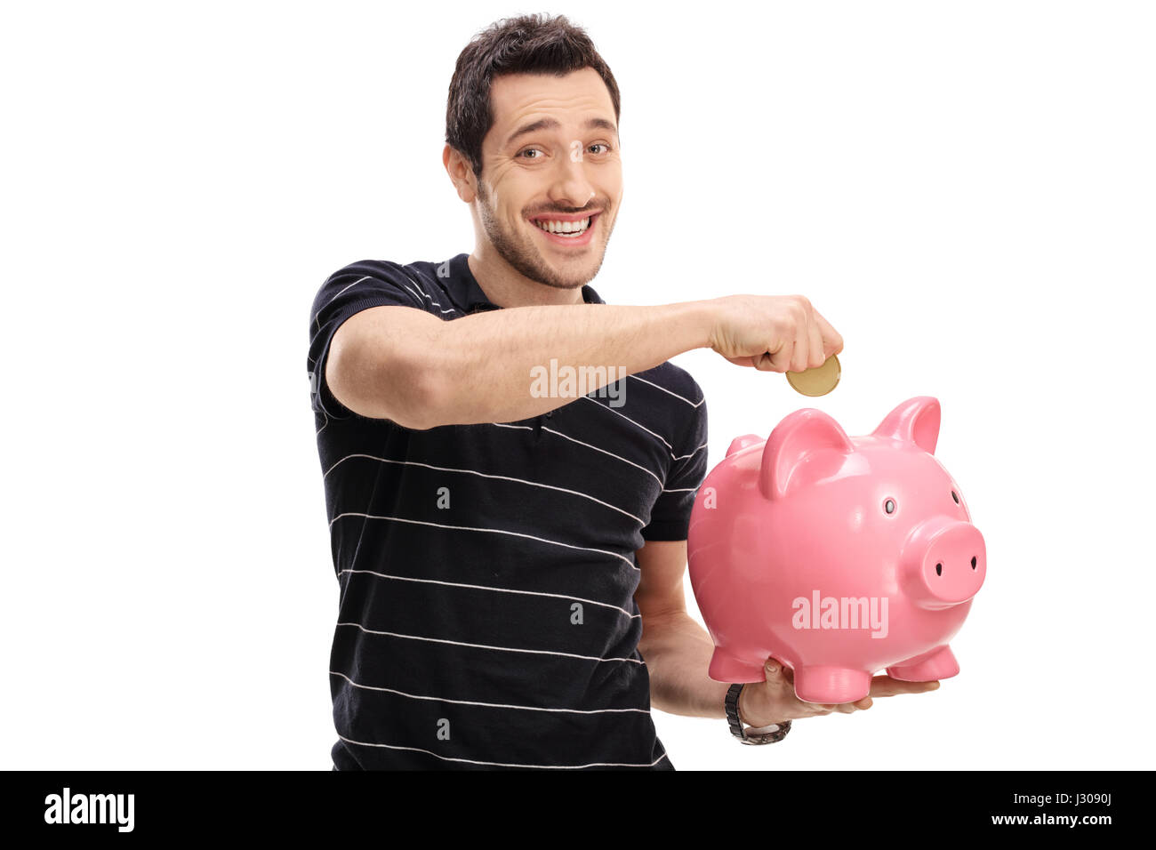 Happy young man putting a coin into a piggybank isolated on white ...
