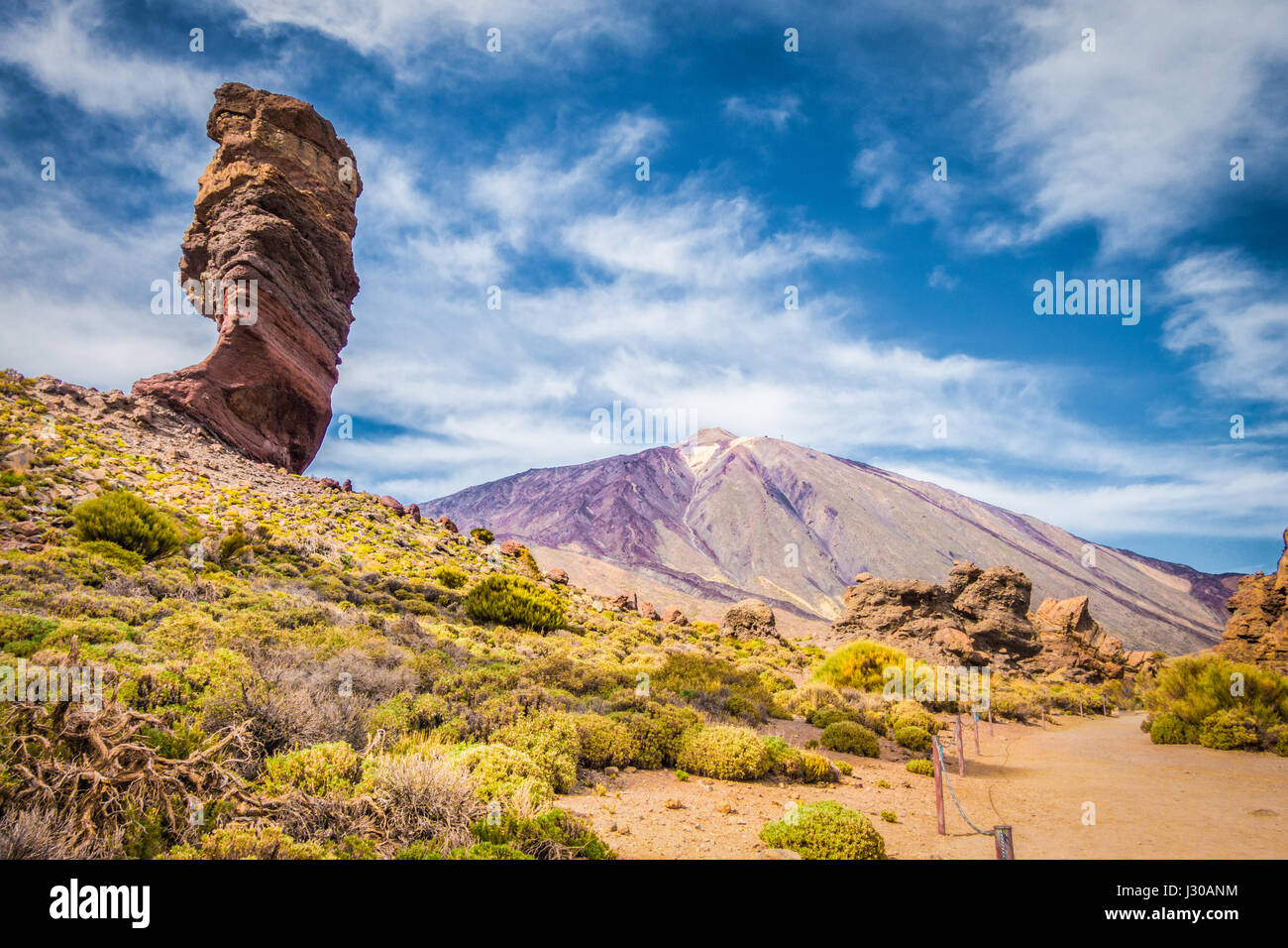 Roque Cinchado unique rock formation with famous Pico del Teide mountain volcano summit in the background on a sunny day, Tenerife, Canaries, Spain Stock Photo