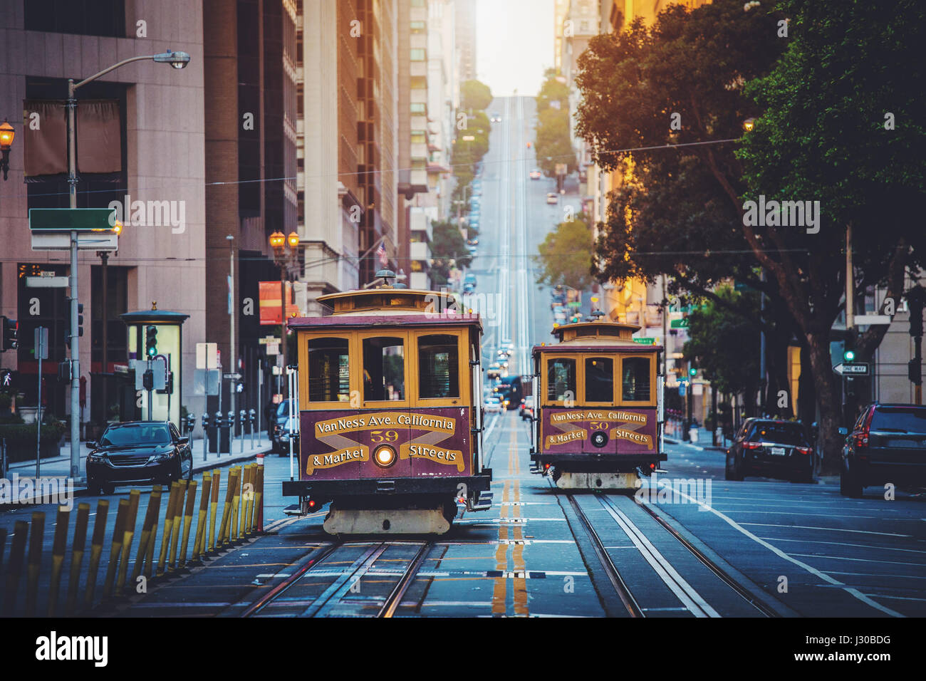 Classic view of historic traditional Cable Cars riding on famous California Street in beautiful early morning light at sunrise in summer with retro vi Stock Photo
