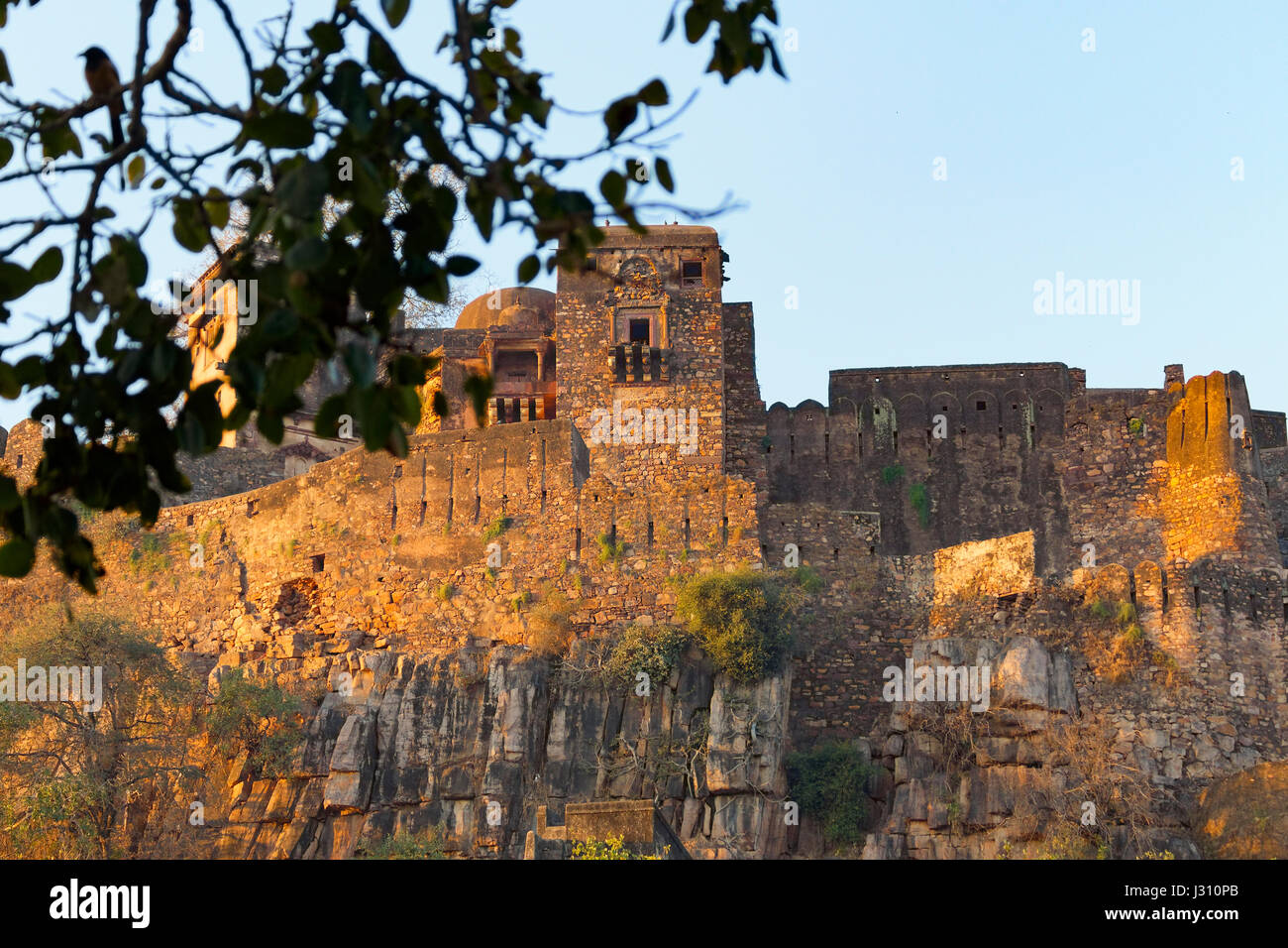 The ruins of Ranthambore Fort on top of a cliff at sunrise Stock Photo