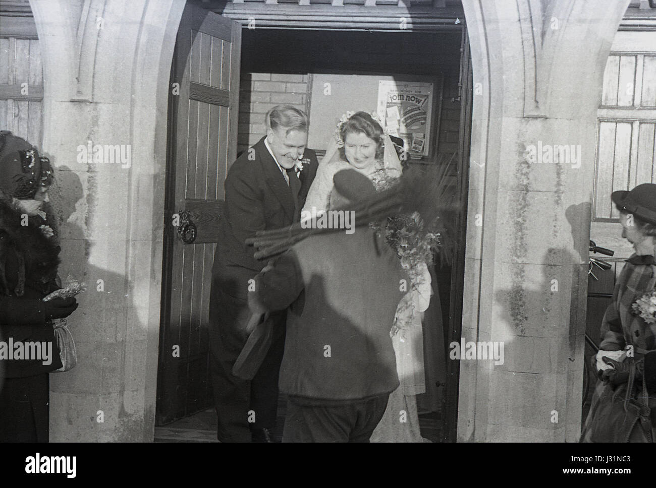 1950s, a newly married couple are greeted at the entrance to the church by a chimney sweep, traditionally a sign of good luck or good fortune, England, UK. Stock Photo