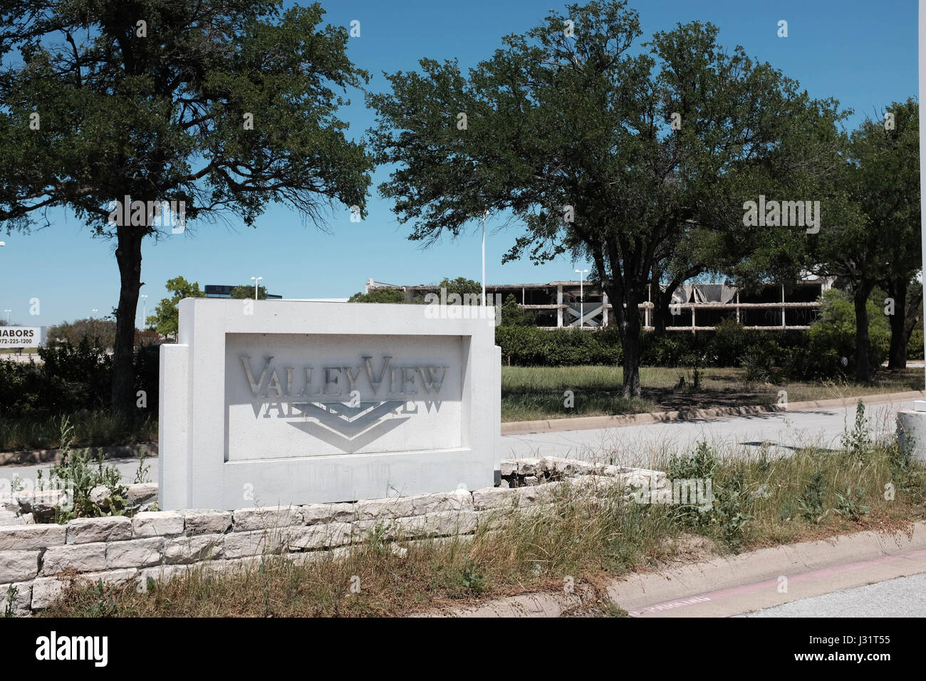 Dallas, Texas USA. 1st May,  2017. Once busy Valley View Mall in North Dallas is shutting down a piece at a time to make room for a new development called 'Midtown'. Weeds at the mall entrance are overgrown. In the background, the shell of the west face of the mall is exposed. credit: Keith Adamek/Alamy Live News Stock Photo