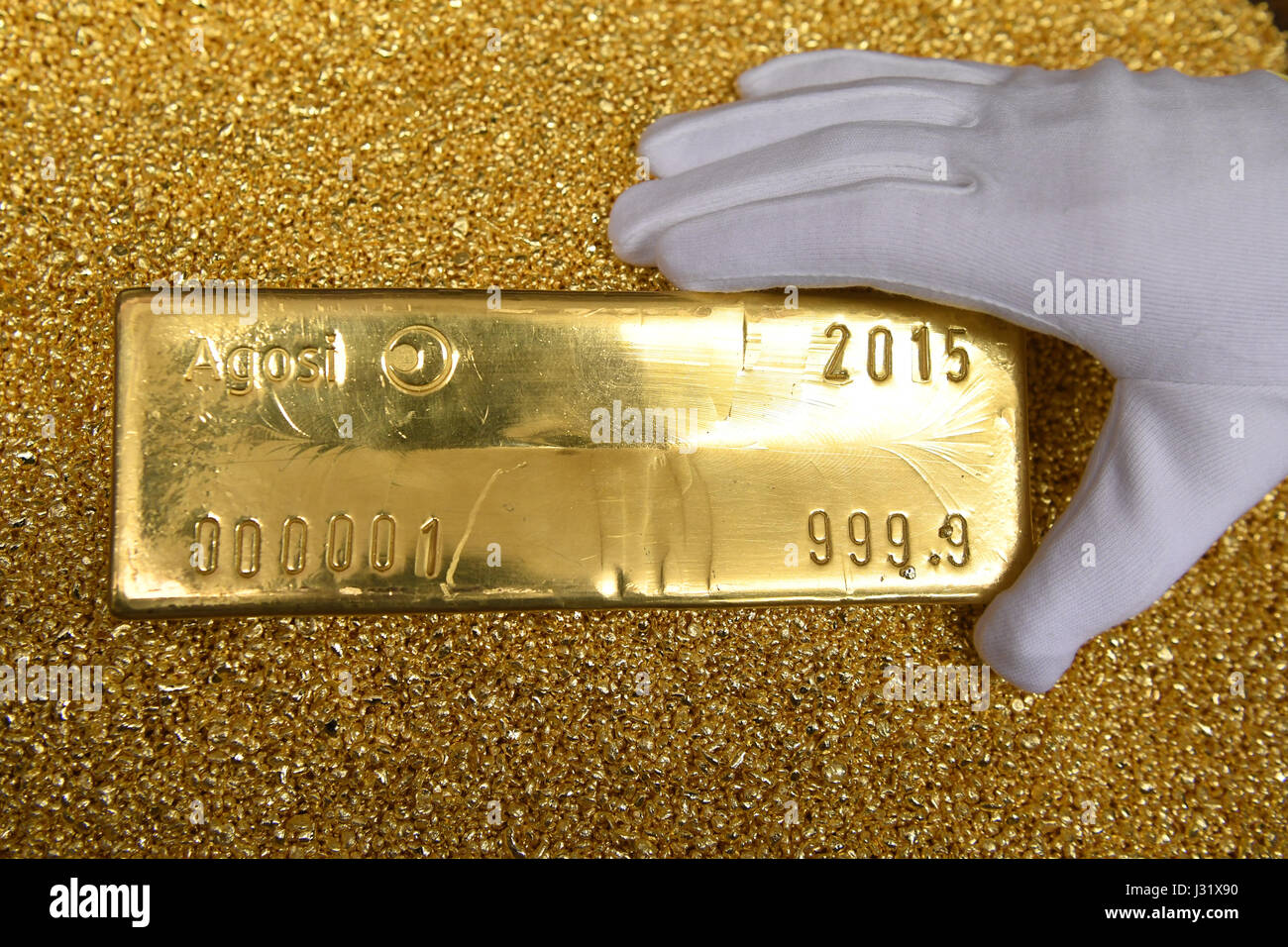 Pforzheim, Germany. 28th Apr, 2017. A gold bar weighing 12.5 kilograms, has  a fine gold content of 99.99 percent against granules of gold at the  company Allgemeine Gold- und Silberscheideanstalt Agosi in