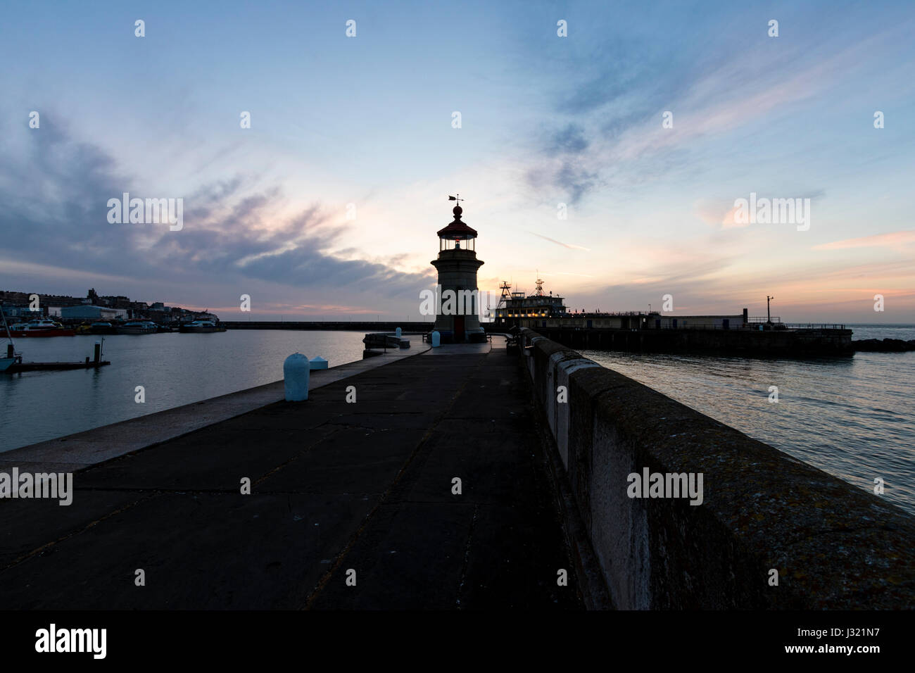 England, Ramsgate harbour. Dawn sky with silhouette lighthouse at end of harbour jetty, and in the background, the harbour offices on other harbour jetty. Sky with cloud layer, sunrise hidden. Stock Photo